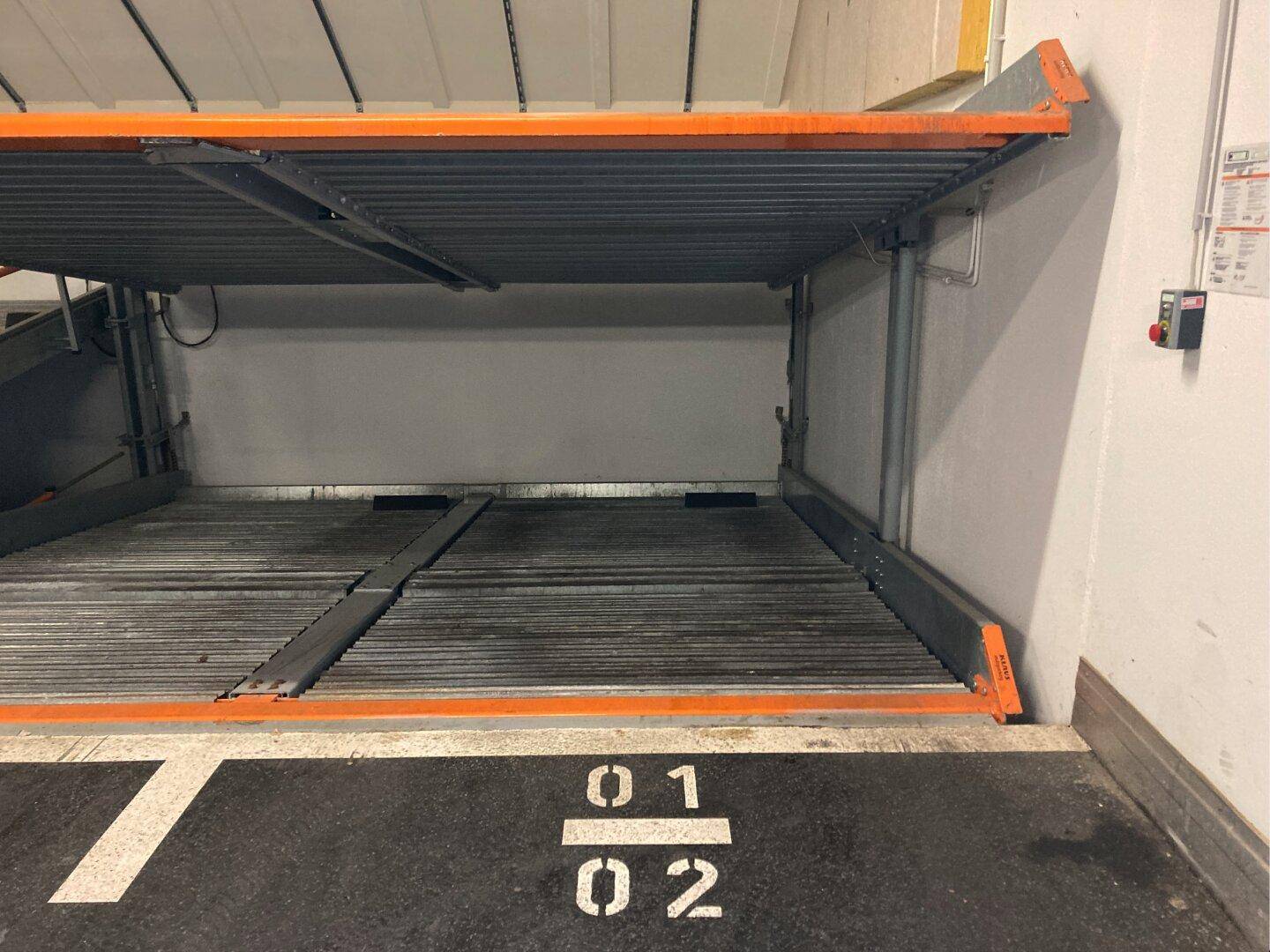 Zweites Bild des mechanischen Doppelparkersystems in der Tiefgarage mit markierten Stellplätzen und Metallkonstruktion.
