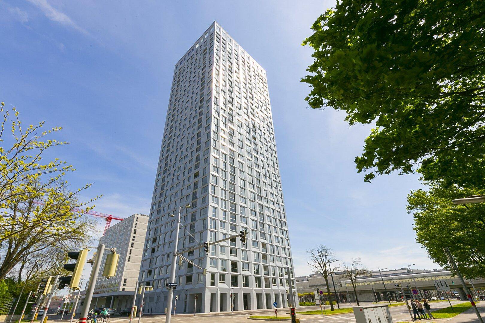 Hohes, modernes Gebäude mit markanter Architektur und vielen Fenstern unter blauem Himmel.