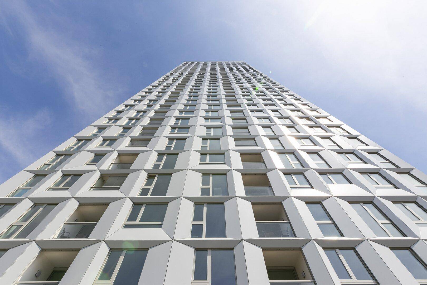 Beeindruckende Fassade eines modernen Hochhauses mit vielen Fenstern und geometrischen Mustern.