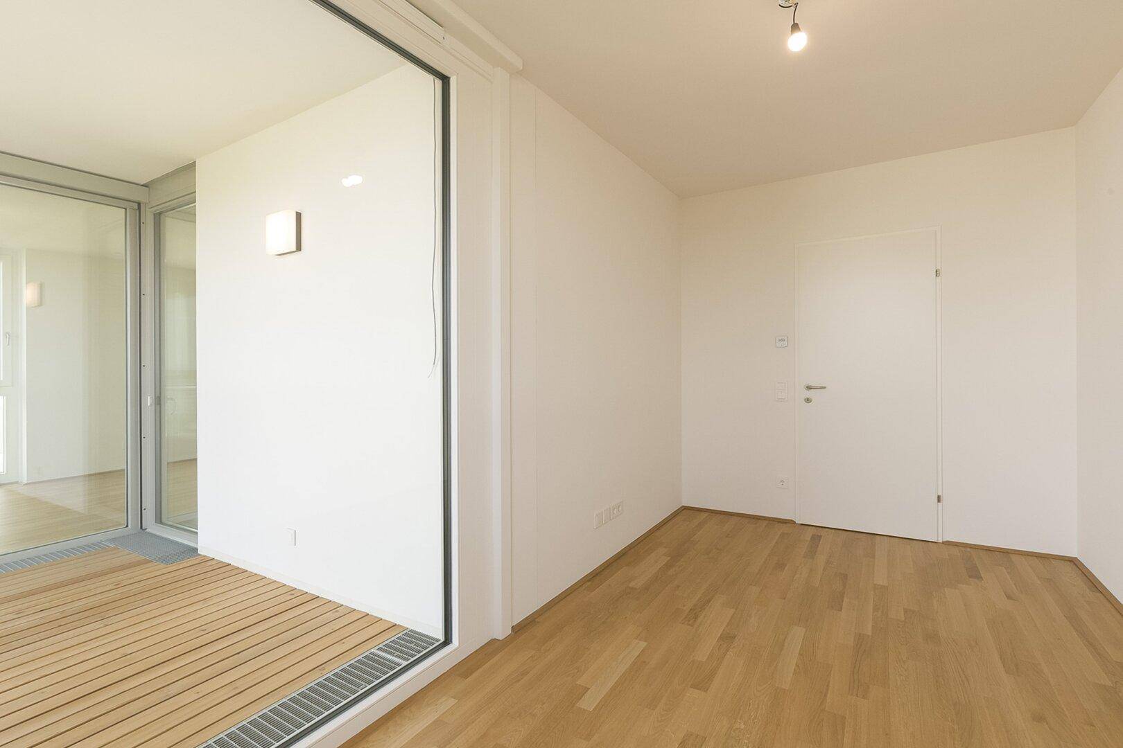 Heller Flur mit Parkettboden und einer Tür, die zu einem weiteren Raum oder zur Loggia führt.
