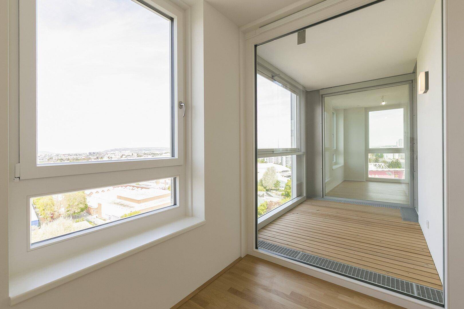 Verglaste Loggia mit Holzboden und weitem Ausblick, die als erweiterter Wohnraum genutzt werden kann.