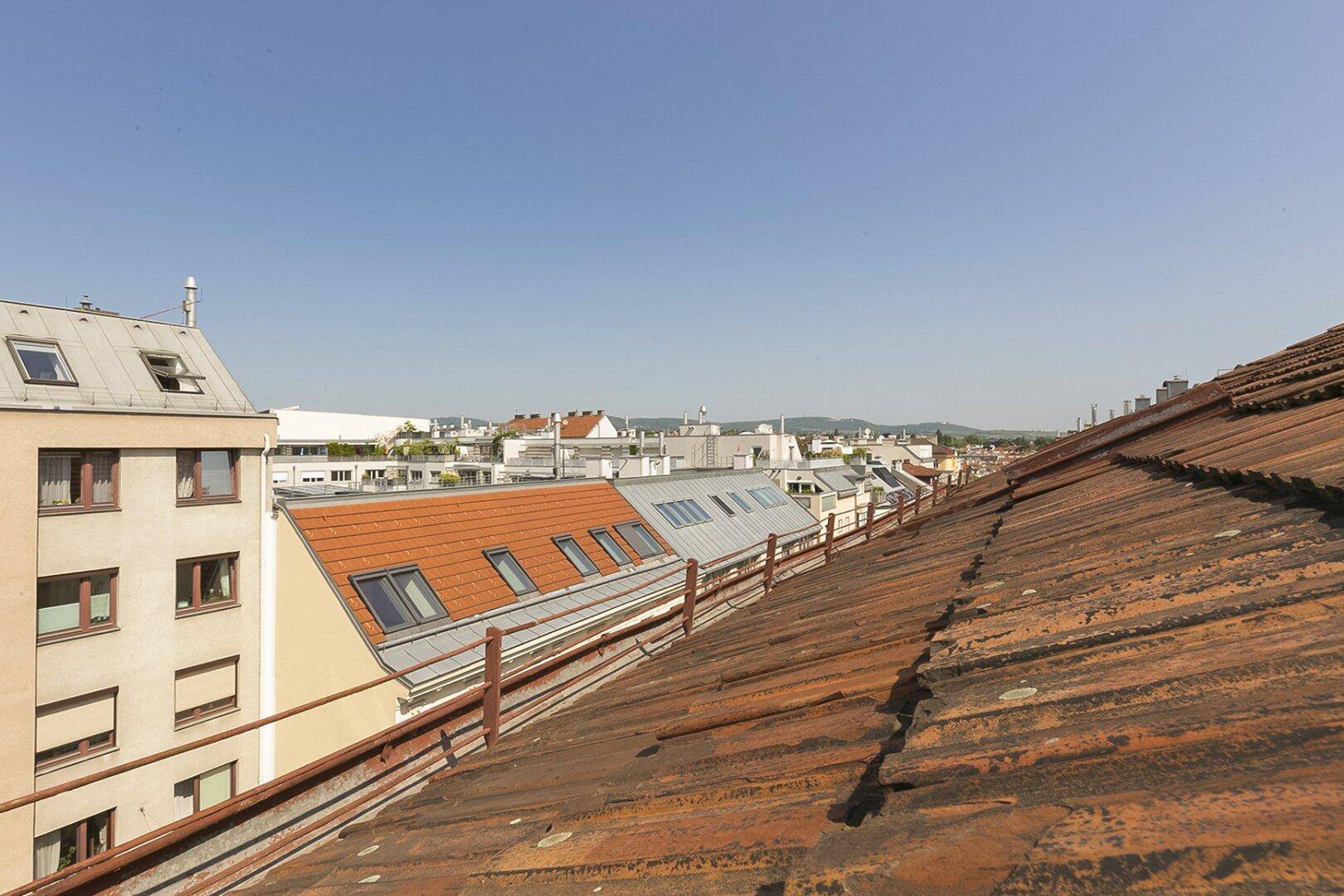 Blick über die Dächer der Stadt mit alten Ziegeln und weitem Horizont unter blauem Himmel.