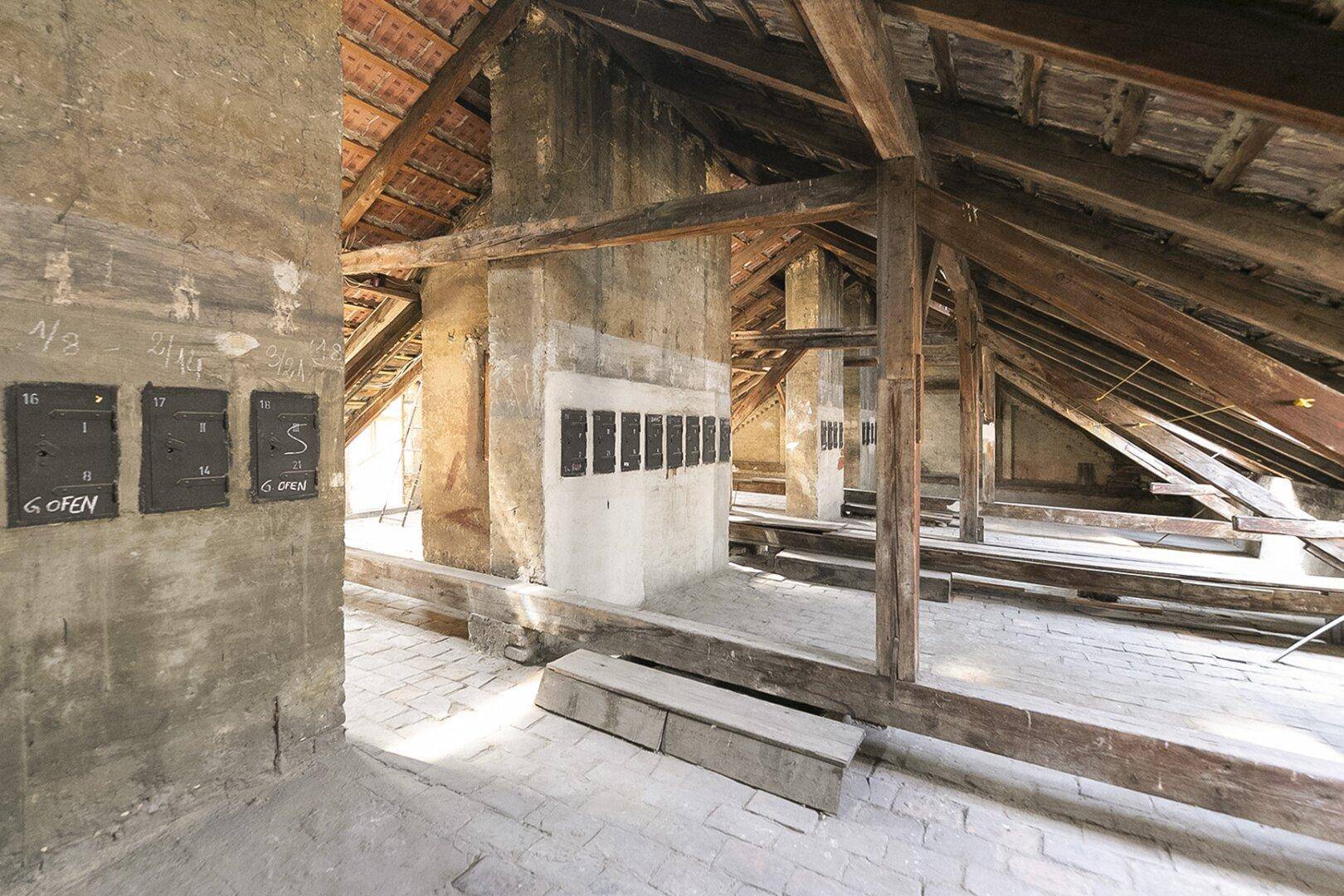 Unausgebauter Dachbodenbereich mit robusten Holzbalken und alten Schornsteinschächten.