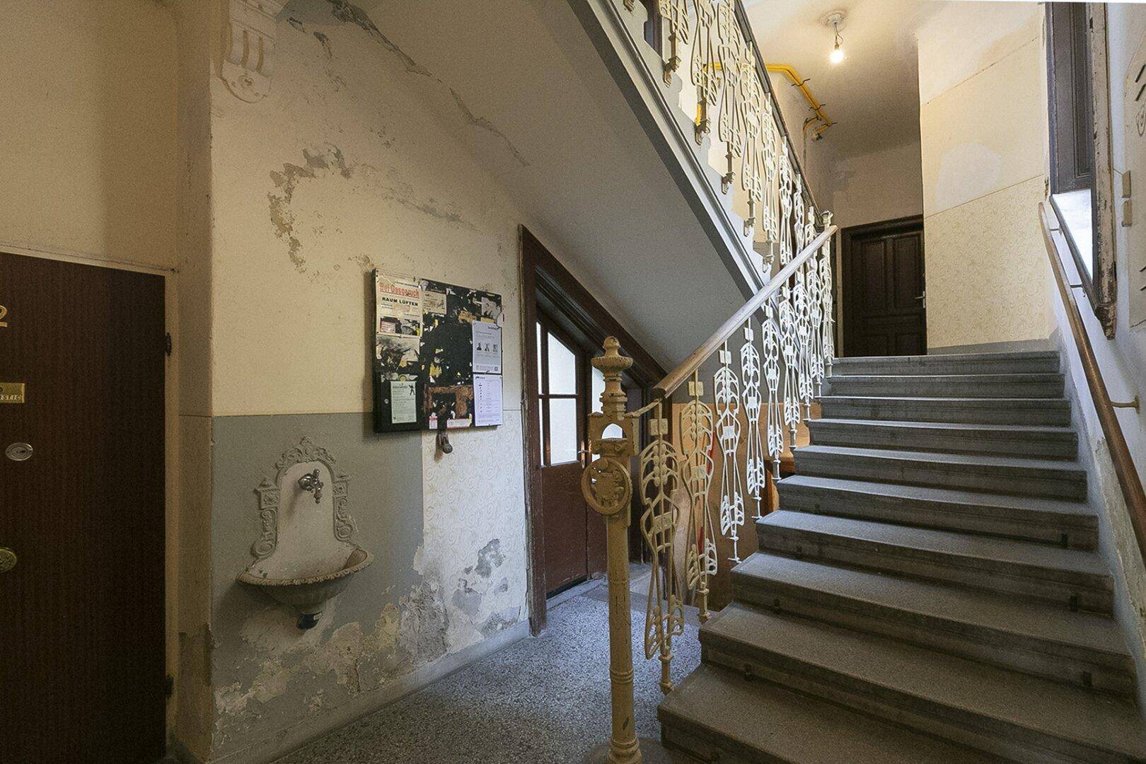 Eingangsbereich des Treppenhauses mit dekorativem Wandbrunnen und historischem Charme.