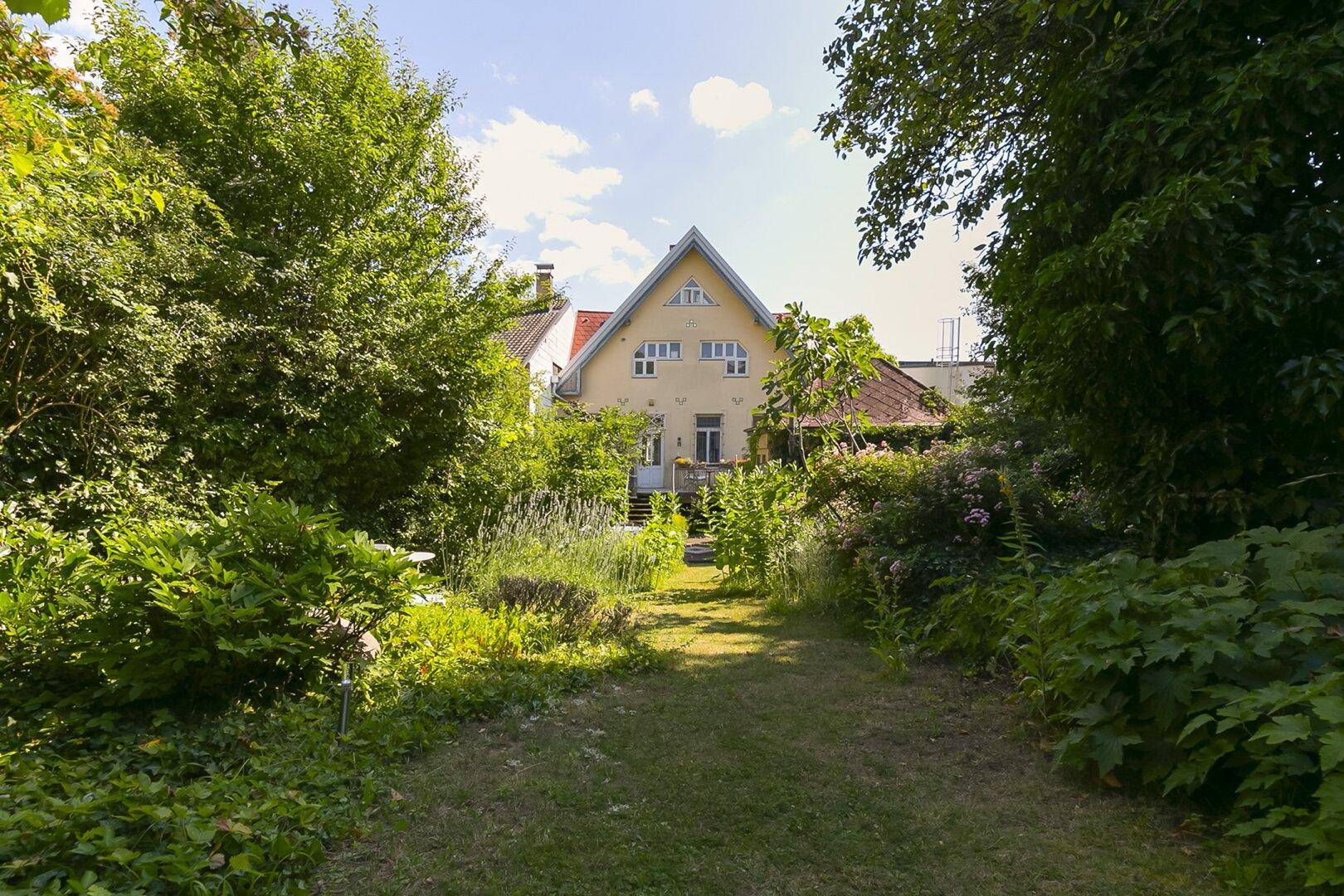 Großer, naturbelassener Garten mit Rasenweg und Blick auf das Haupthaus im Hintergrund.
