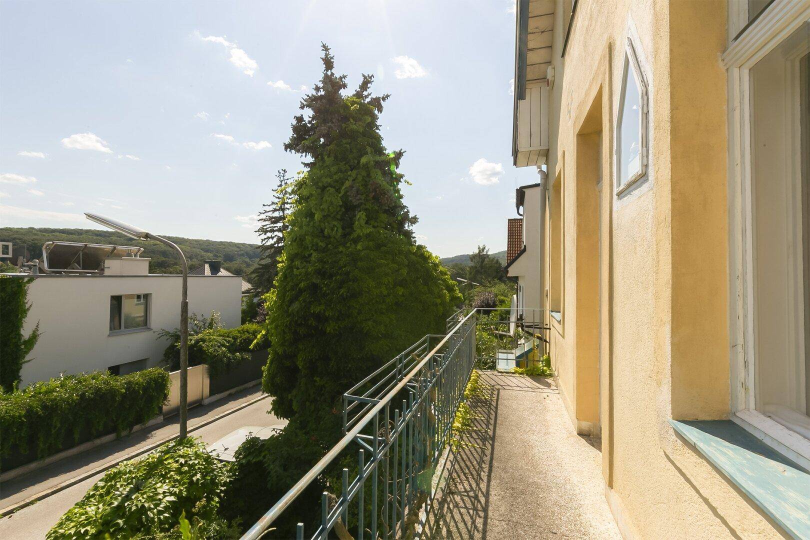 Langer Balkon mit Metallgeländer und weitem Blick über die bewaldete Hügellandschaft.
