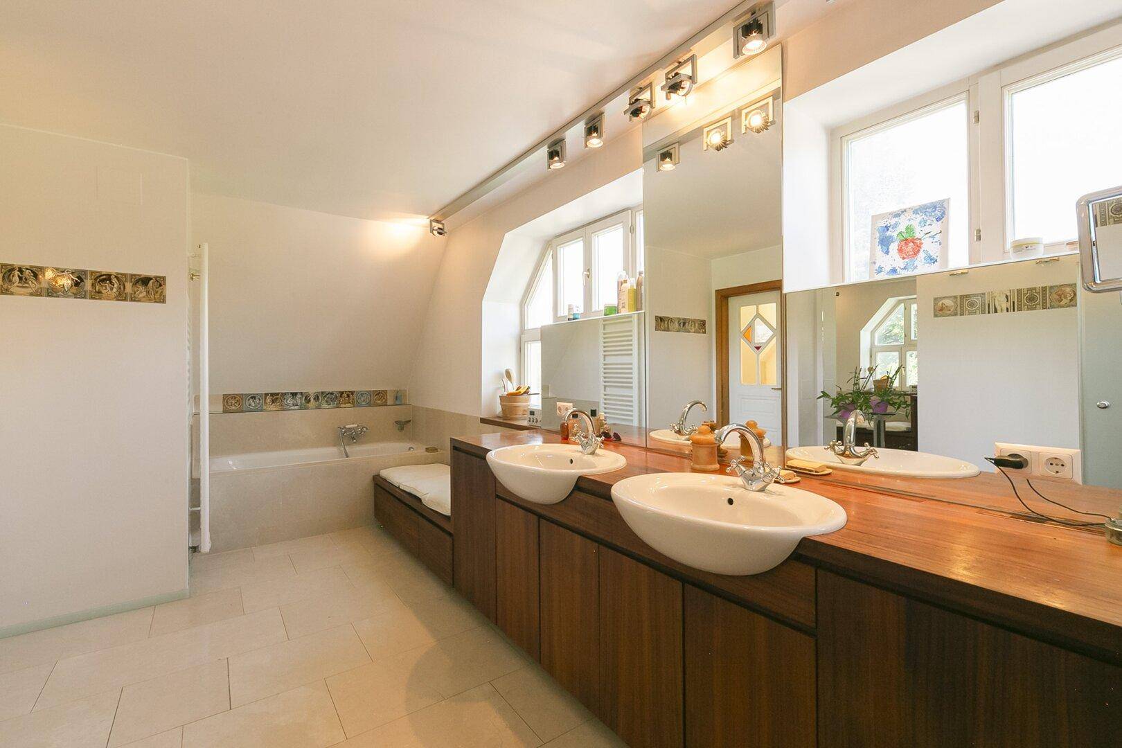 Modernes Badezimmer mit Badewanne, Doppelwaschbecken und großen Spiegeln.