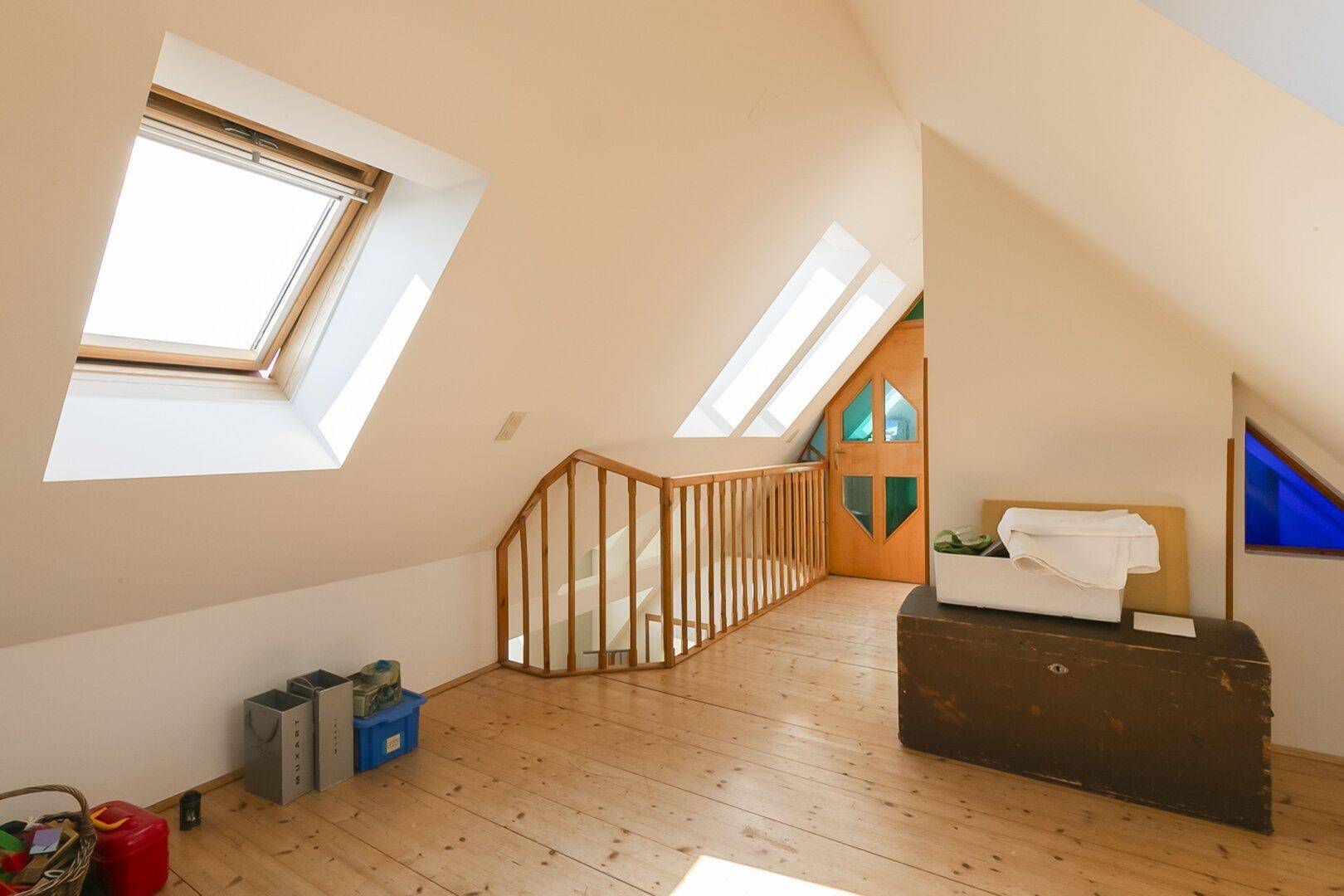 Dachgeschoss mit Holzboden, Dachfenstern und Stauraum.