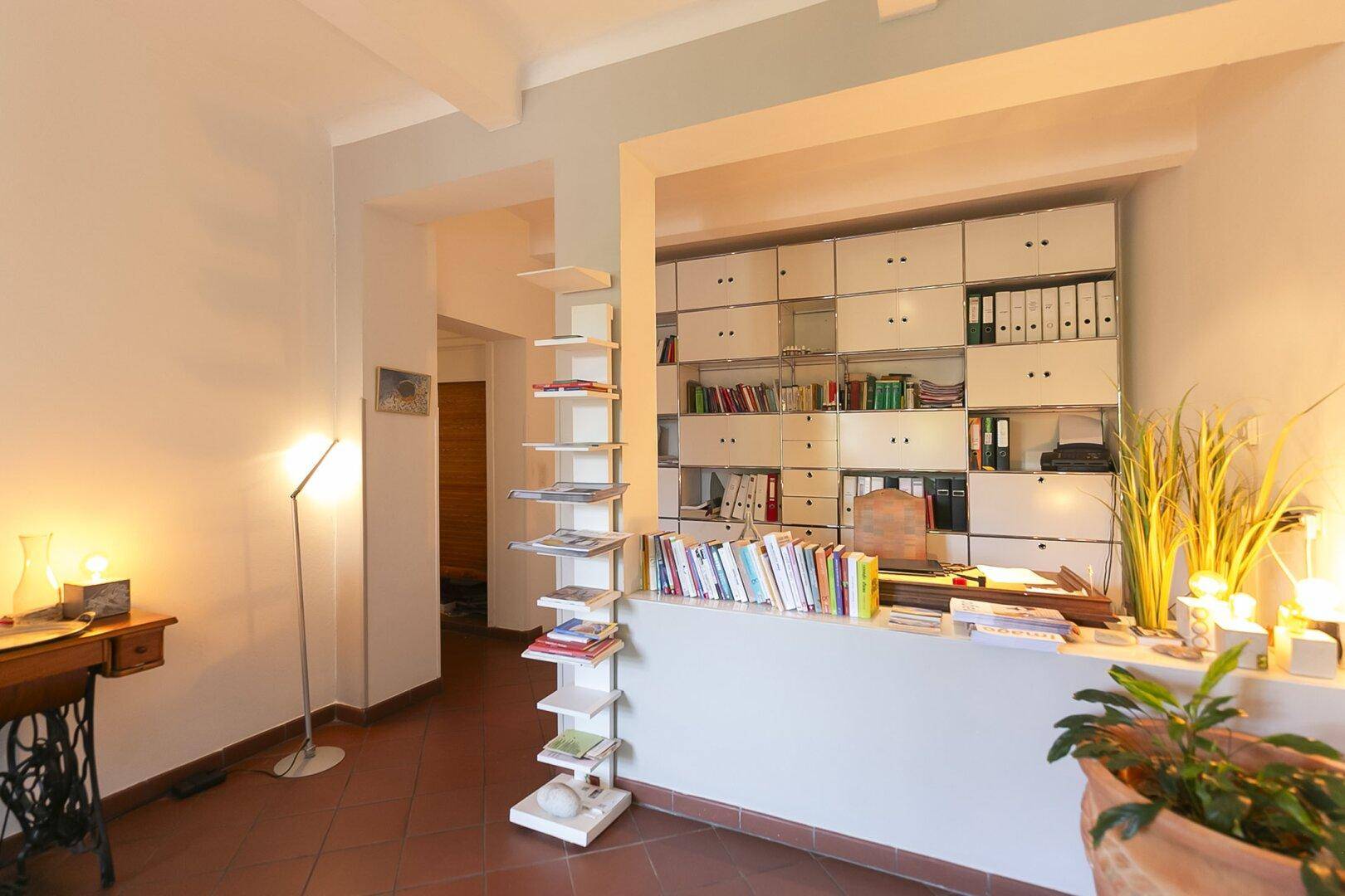 Geräumiges Arbeitszimmer mit umfangreichen Regalsystemen und Terrakottafliesen.