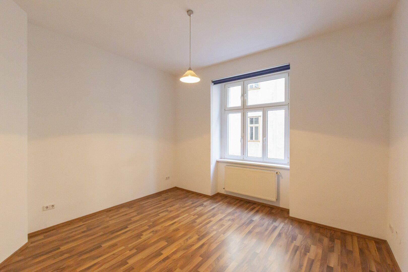 Helles Zimmer mit Laminatboden und einem Fenster, das für gute Belichtung sorgt.