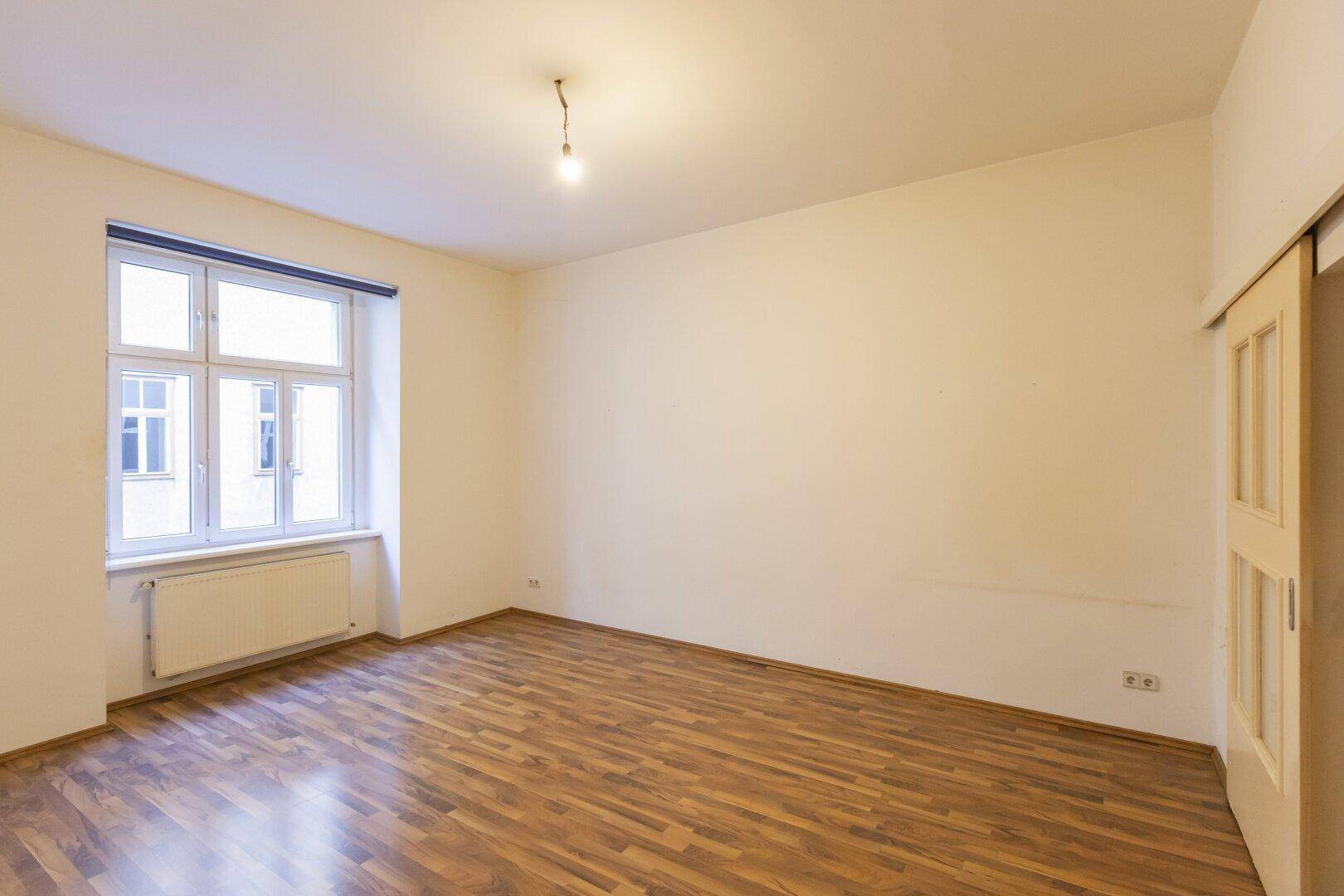 Geräumiges Zimmer mit Laminatboden und einem Fenster, das den Blick nach draußen freigibt.