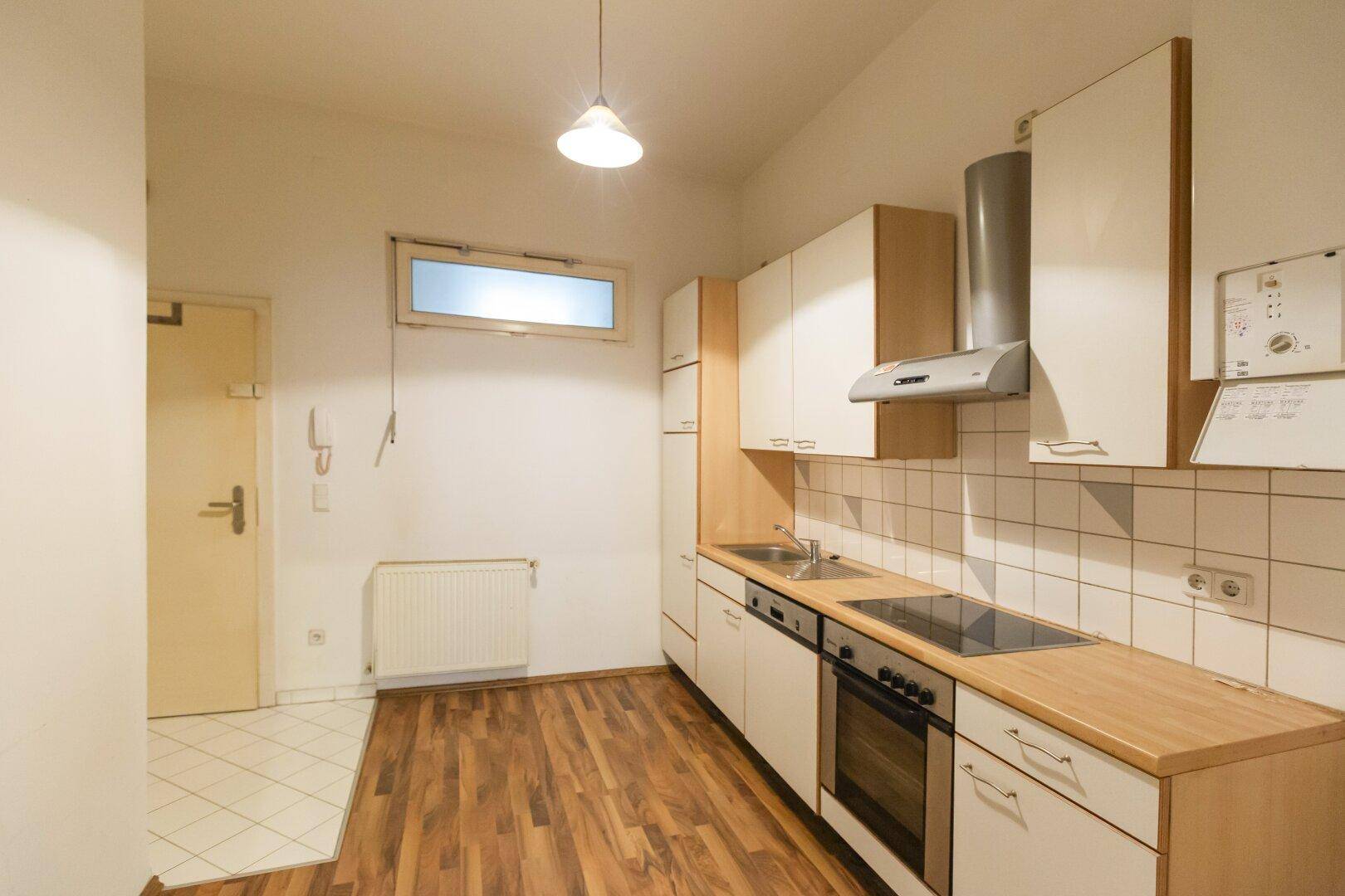 Funktionale Küche mit weißen Schränken, Holz-Arbeitsplatte und Fliesen-Rückwand.