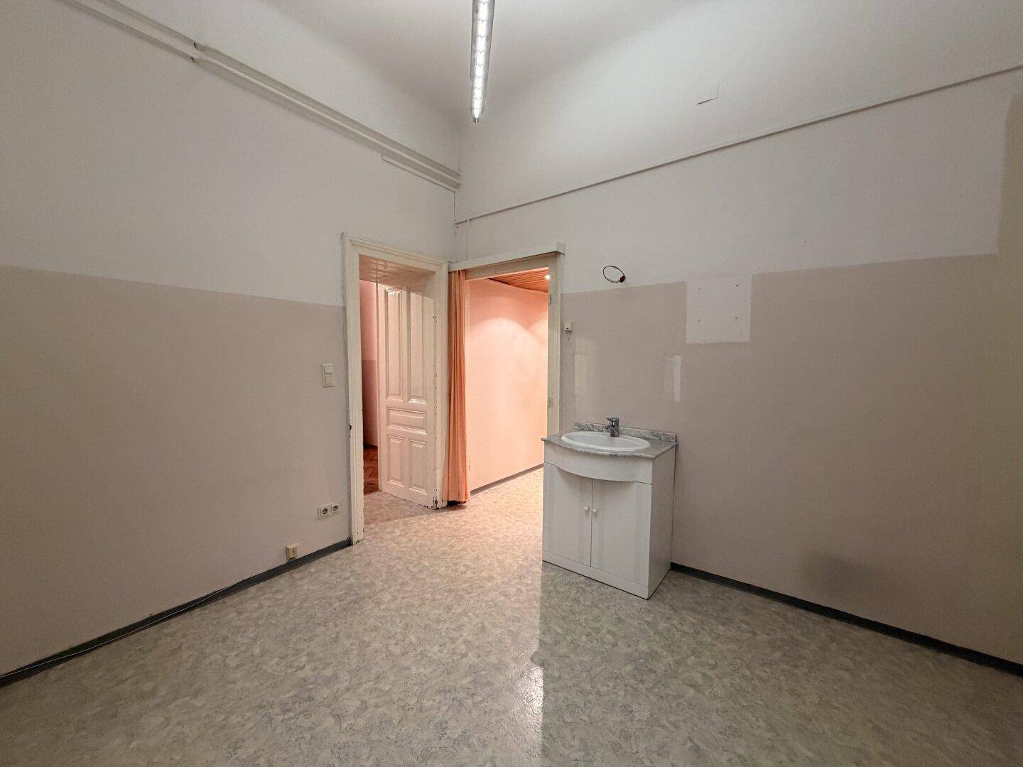 Unmöblierter Raum mit Waschbecken und Linoleumboden, der auf eine Modernisierung wartet.