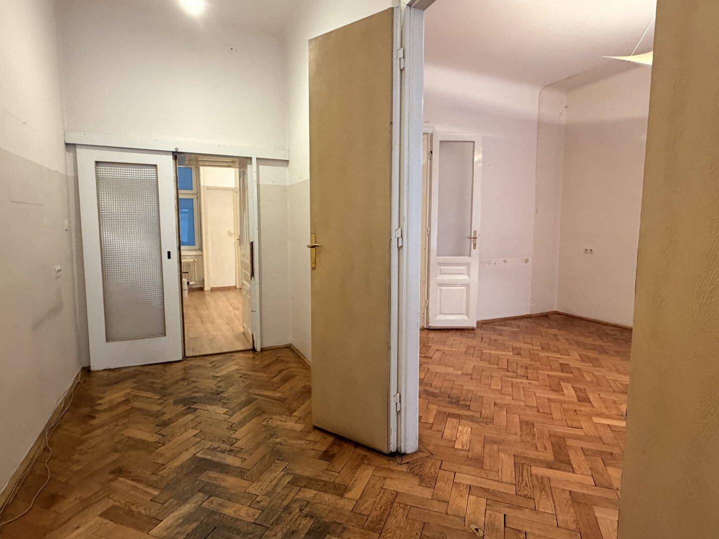 Raum mit Fischgrätparkett und Schiebetüren, der auf eine Modernisierung wartet.