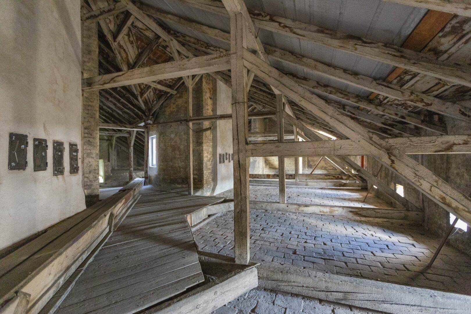 Geräumiger Dachboden mit freiliegenden Holzbalken und Ziegelboden, bereit für einen Ausbau.