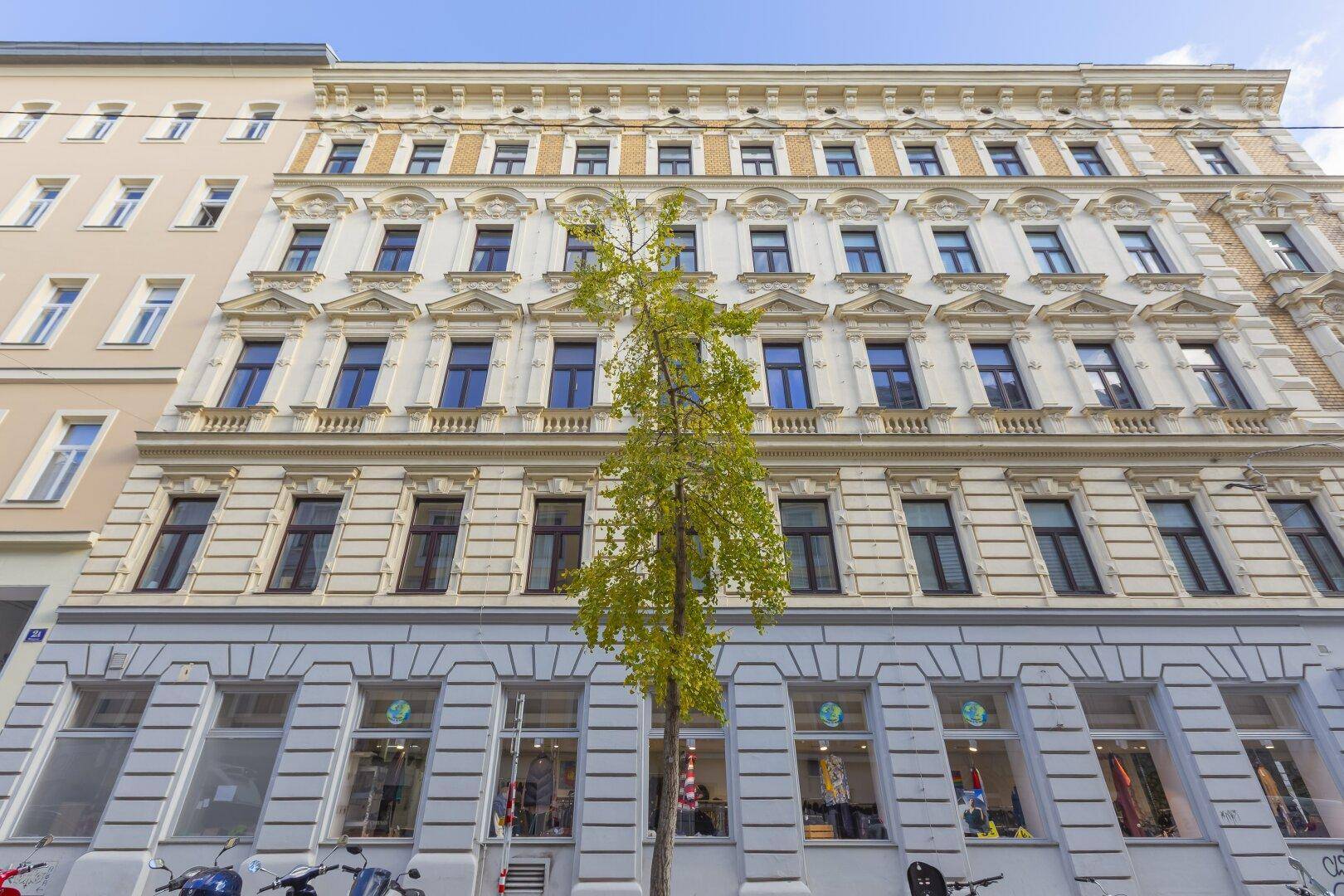 Klassische Fassade eines Altbaus mit vielen Fenstern und Geschäften im Erdgeschoss.