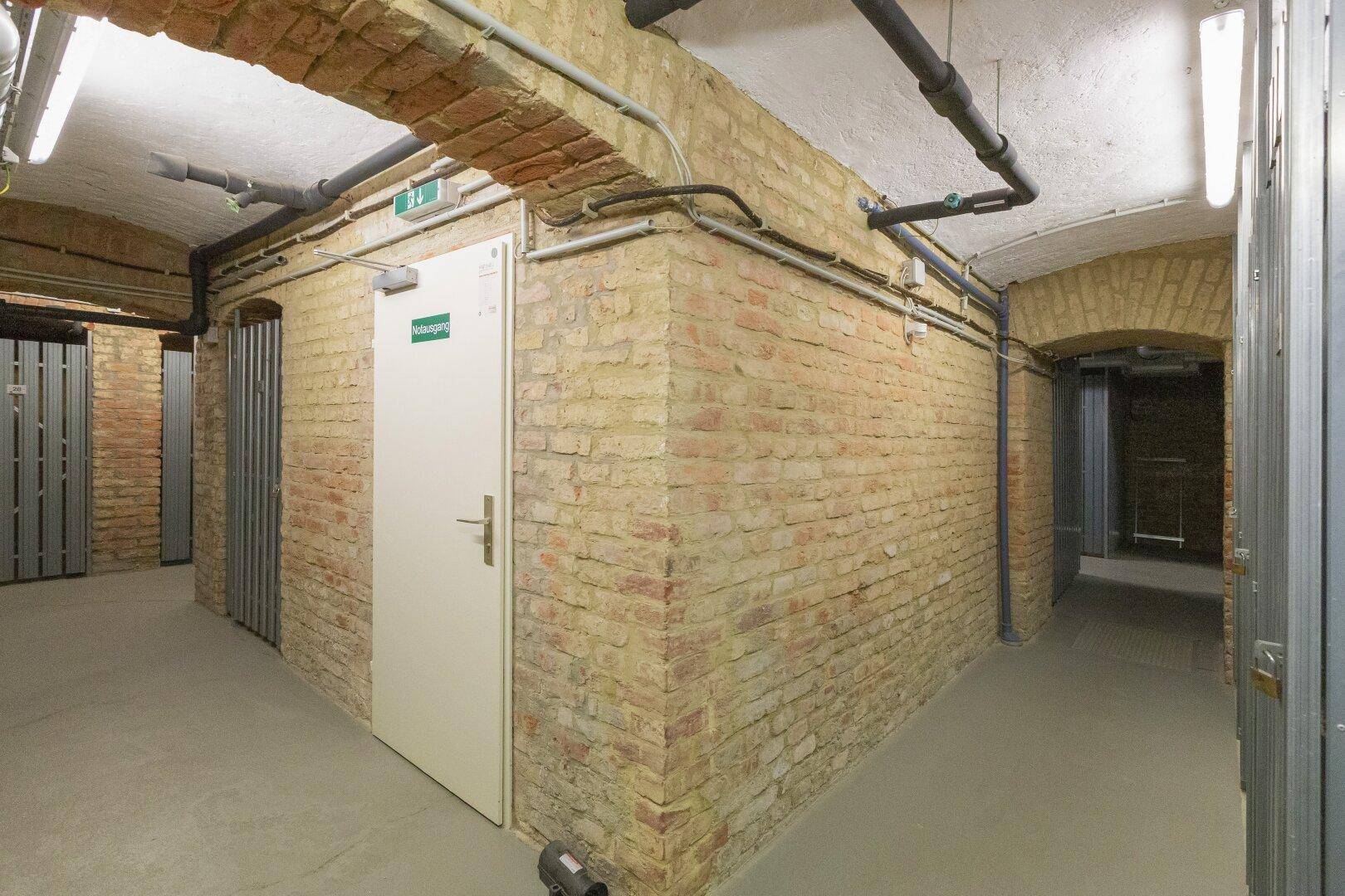 Kellerabteil mit Ziegelwänden und Betonboden, ideal als Stauraum für Bewohner.