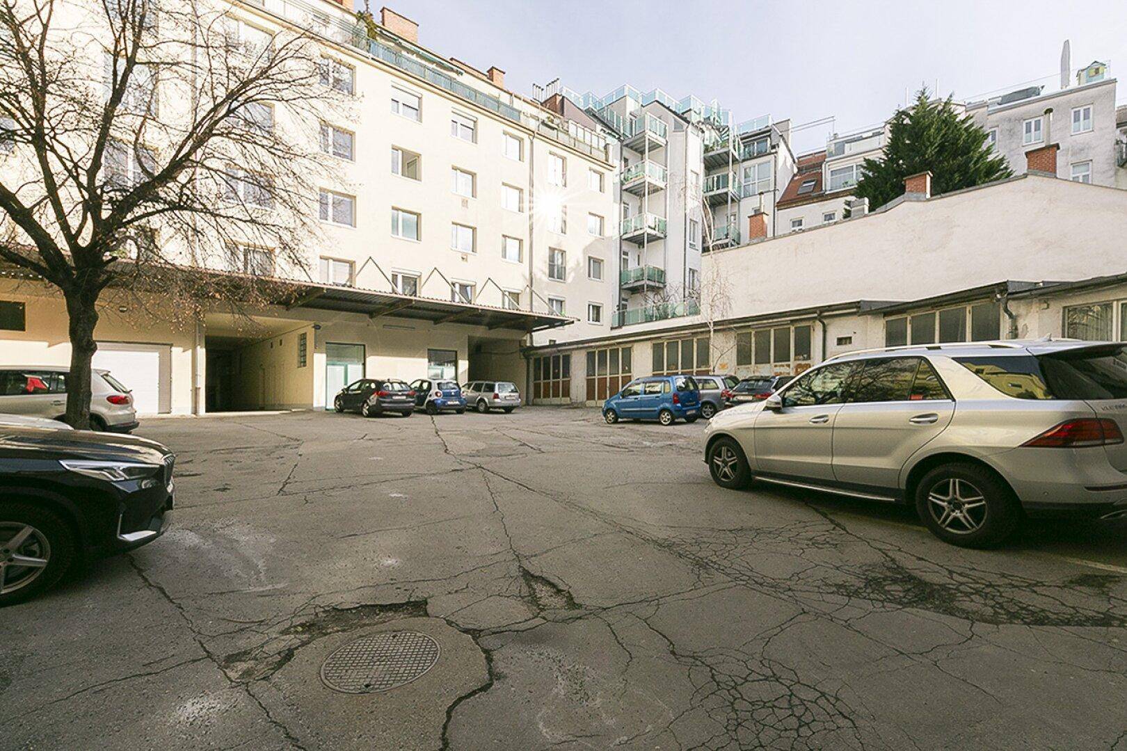 Innenhof mit geparkten Autos und Blick auf die umliegenden Wohngebäude und deren Fassaden.