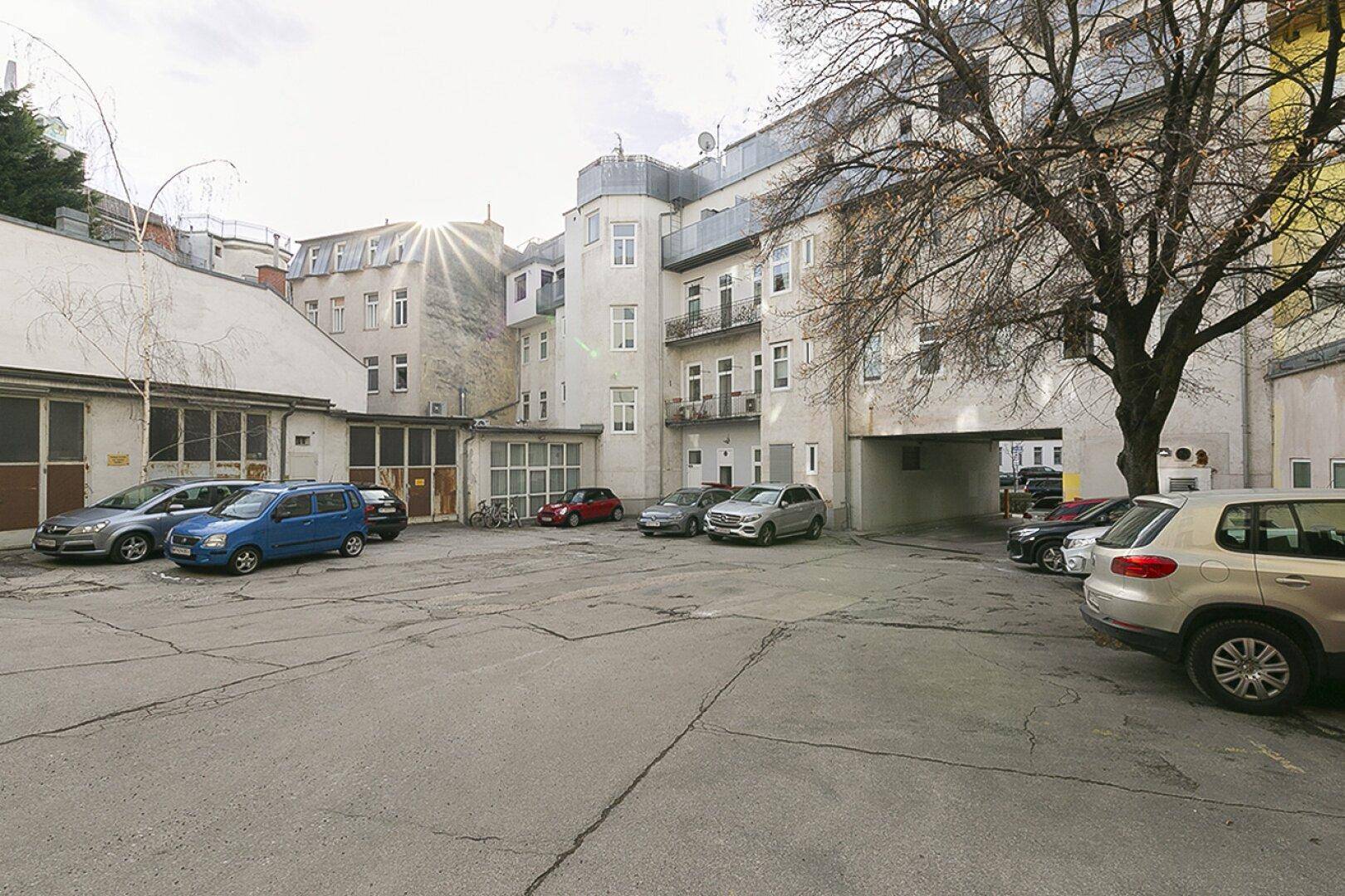 Blick auf den Innenhof mit geparkten Fahrzeugen und den Eingangsbereich zu einer Tiefgarage.