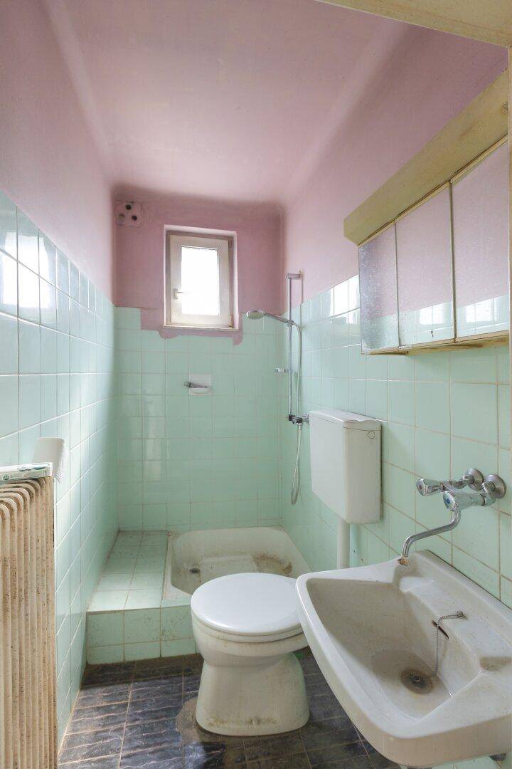 Kleines Badezimmer im Stil der 80er Jahre mit mintgrünen Fliesen und rosa Decke.