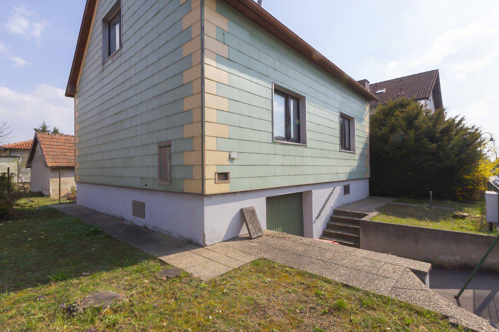 Seitenansicht des Hauses mit Zufahrt zur Garage und Treppe zum Eingangsbereich.