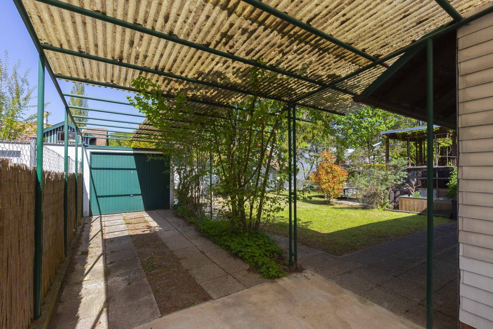 Überdachter Stellplatz und Garagenzufahrt im Außenbereich des Grundstücks.