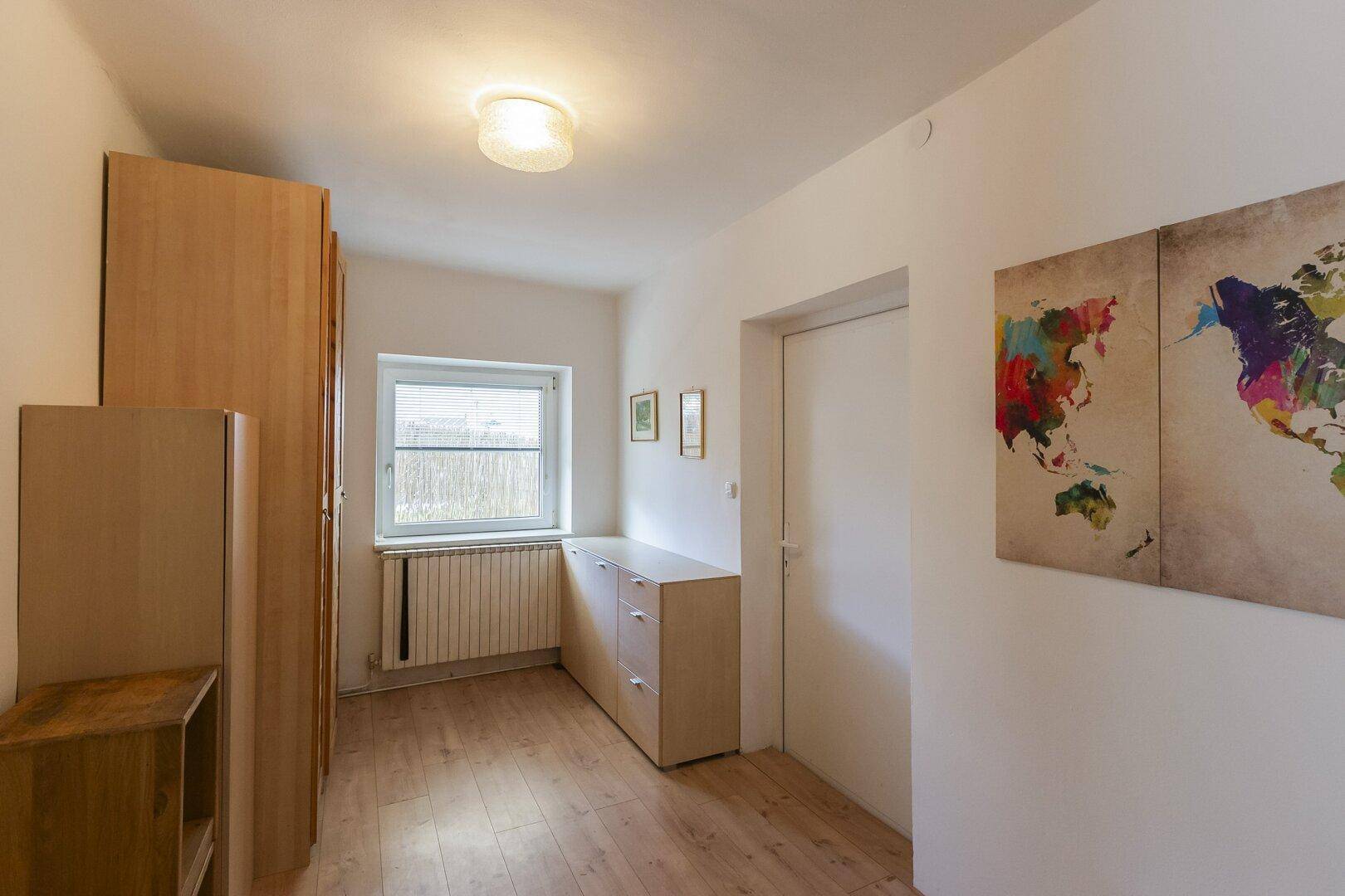 Heller Flur mit Holzboden, Fenster und Stauraum, dekoriert mit einer Weltkarte.