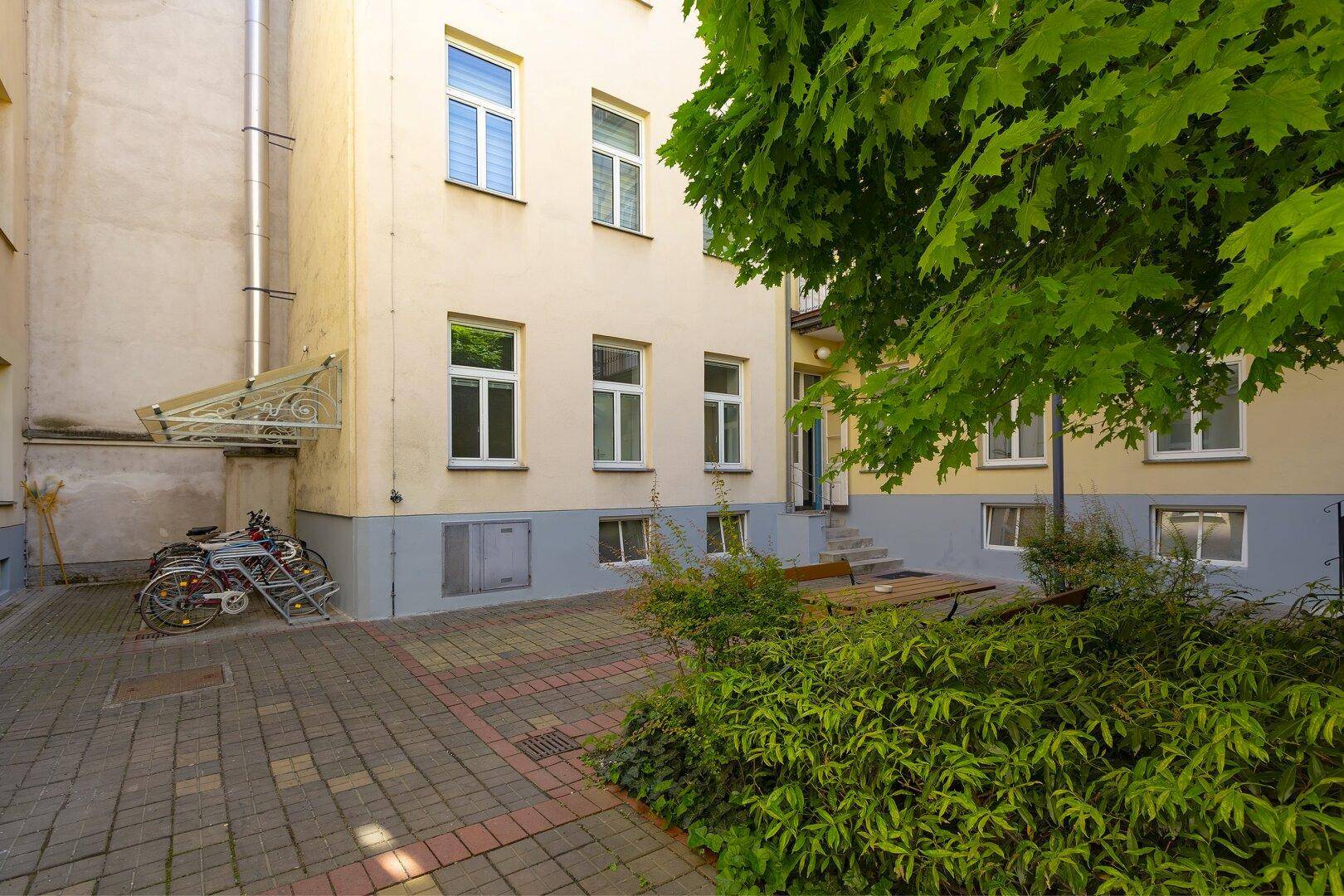 Gepflasterter Innenhof mit Fahrradstellplätzen und üppiger Bepflanzung.