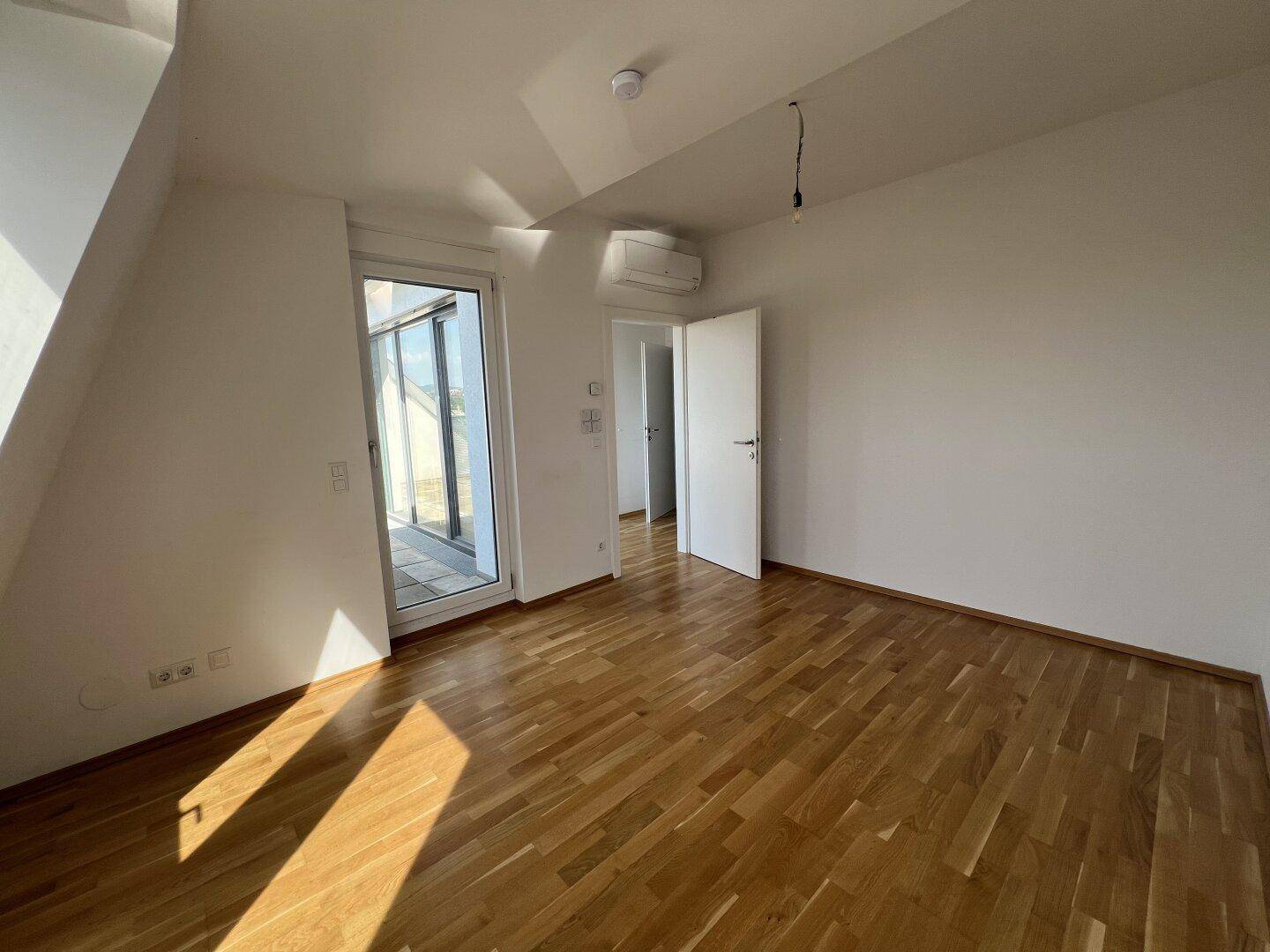 Helles Zimmer mit Holzboden, Klimaanlage und Zugang zur Dachterrasse.