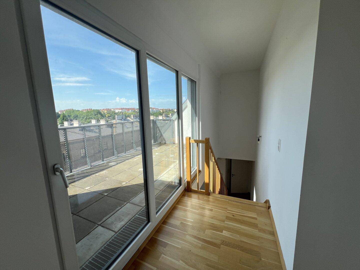 Heller Flur mit Holzboden und großer Glasfront, die zur Dachterrasse führt.