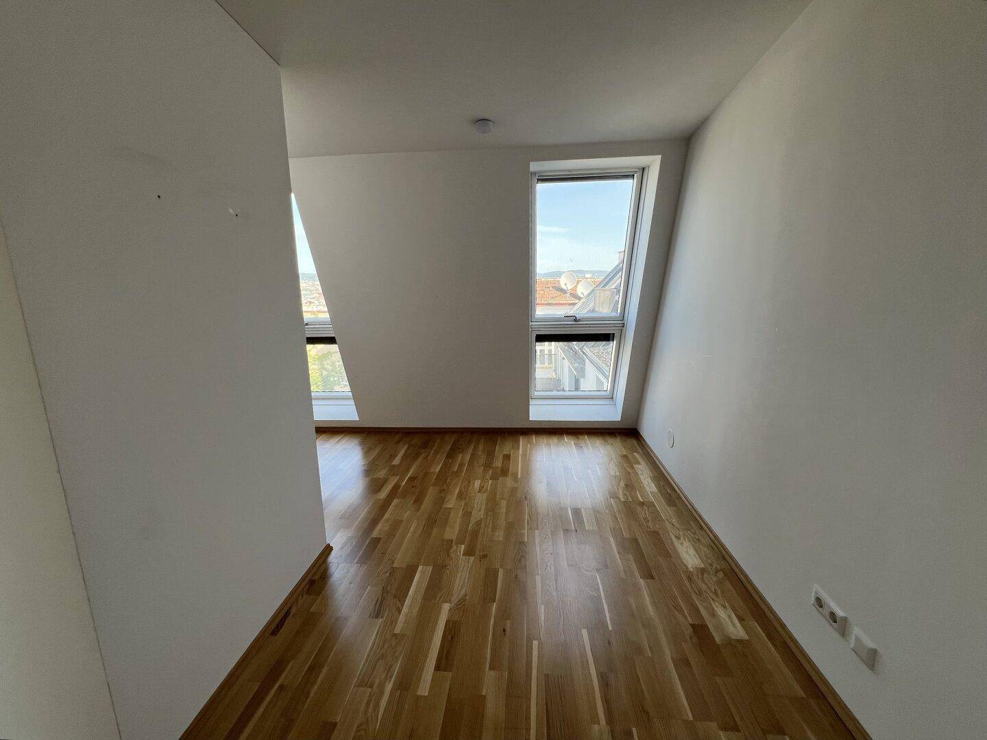 Gemütliches Zimmer mit Holzboden und schrägen Dachfenstern, die viel Licht spenden.