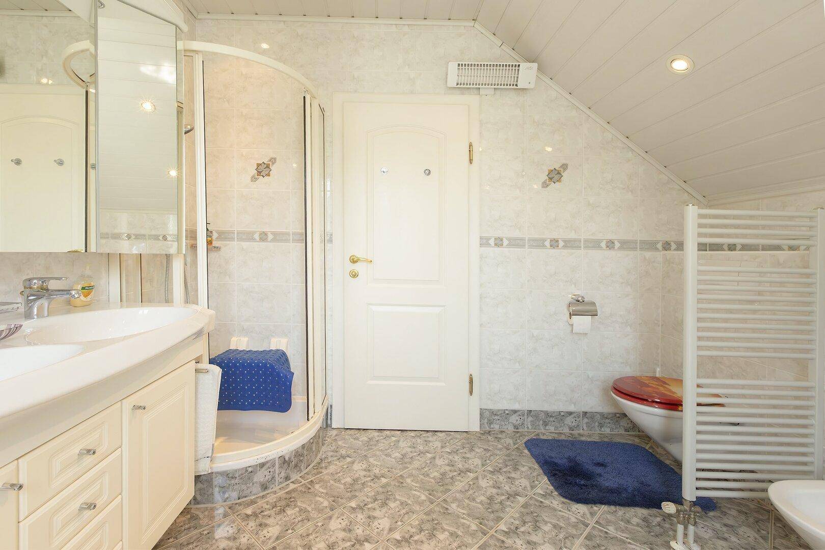 Badezimmer mit Duschkabine, Toilette und beheiztem Handtuchhalter.