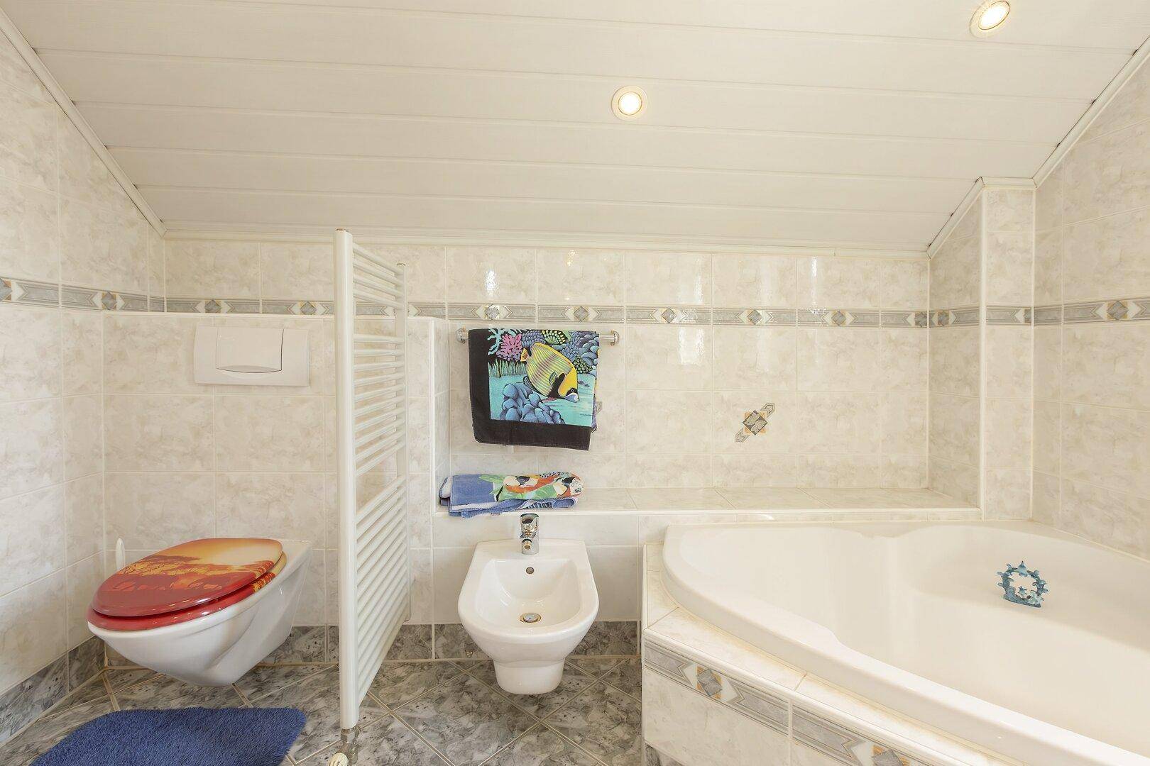 Badezimmer mit Toilette, Bidet und Eckbadewanne.