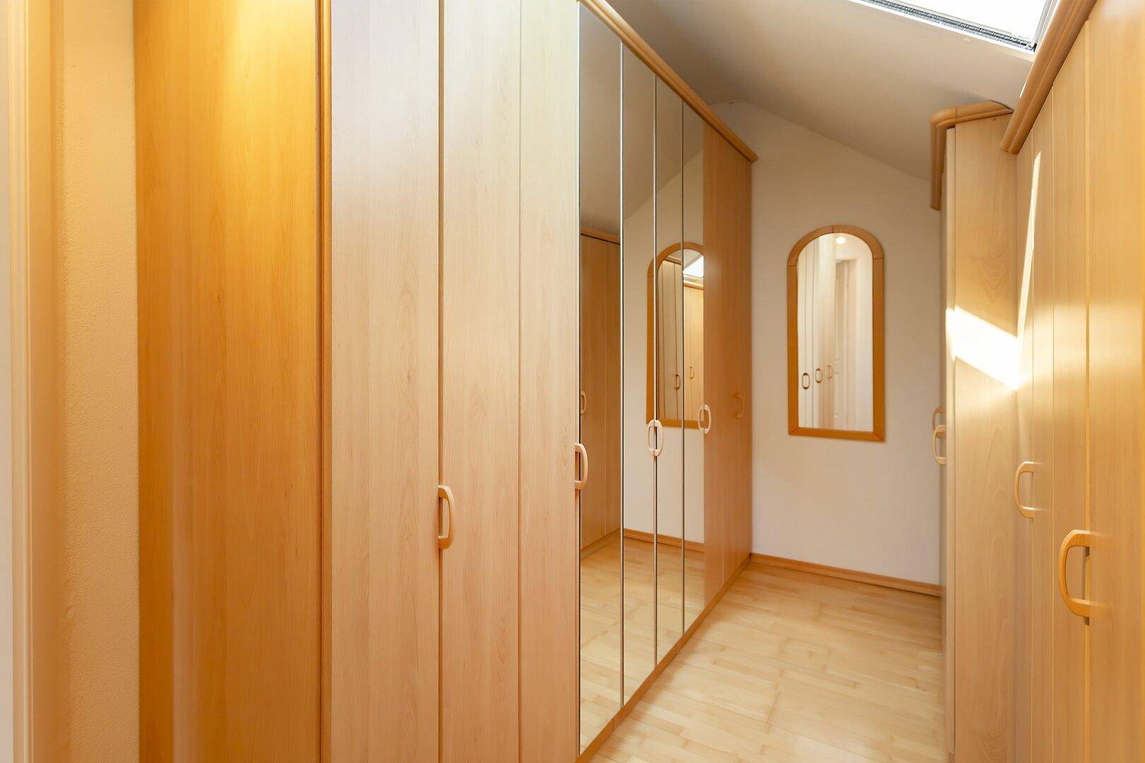 Geräumiger Flur mit Einbauschränken und Spiegeltüren unter einem Dachfenster.
