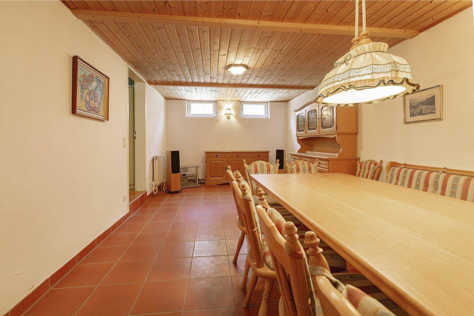 Rustikaler Essbereich im Keller mit Holztisch, Bänken und Terrakottafliesen.