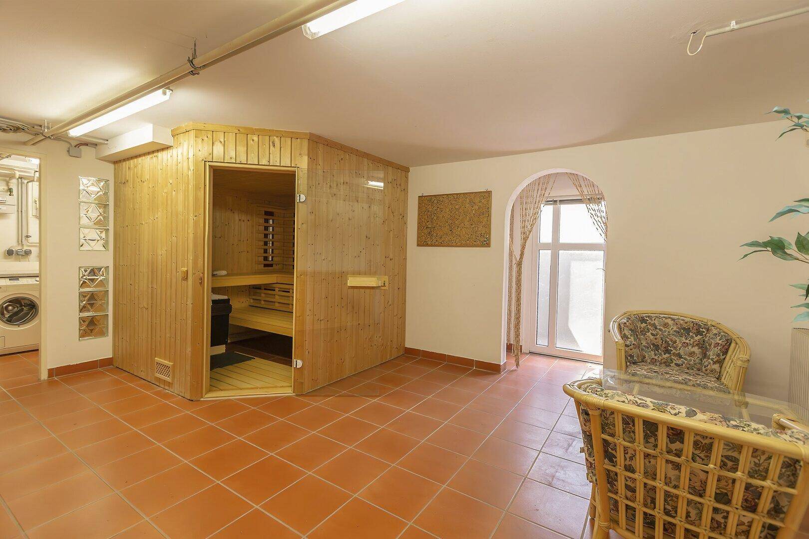 Wohnkeller mit Sauna, Rattanmöbeln und Terrakottafliesen.
