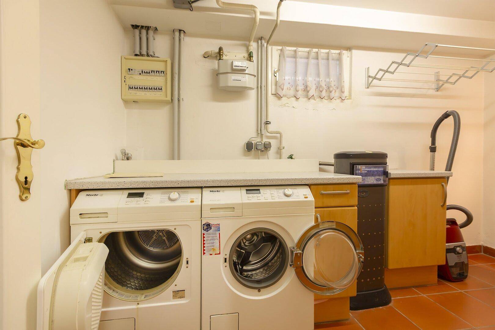 Waschküche im Keller mit Waschmaschine, Trockner und Gaszähler.