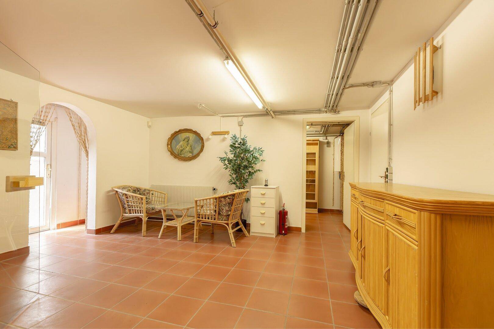 Heller Wohnkeller mit Rattanmöbeln und Terrakottafliesen.