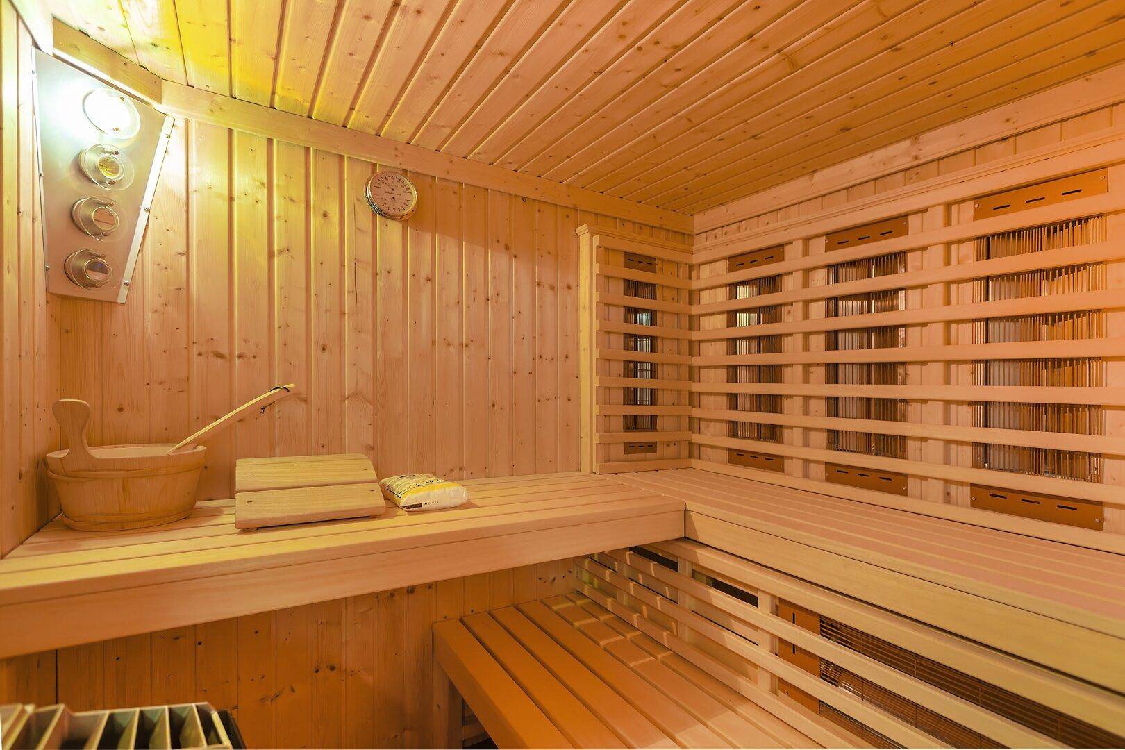 Innenansicht einer Holzsauna mit Bänken und traditionellem Saunaofen.