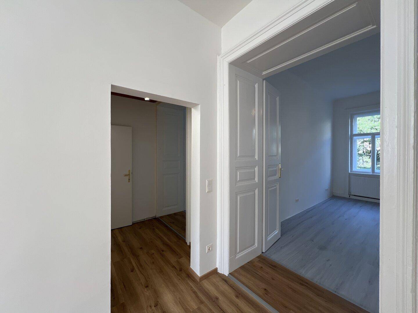 Flur mit Holzlaminatboden und weißen Türen, der zu verschiedenen Räumen führt.