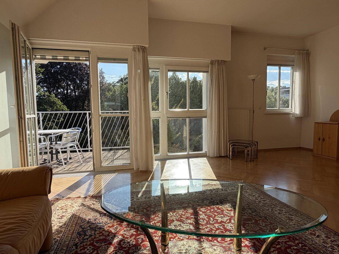 Helles Wohnzimmer mit Zugang zum Balkon, großen Fenstern und viel Tageslicht.