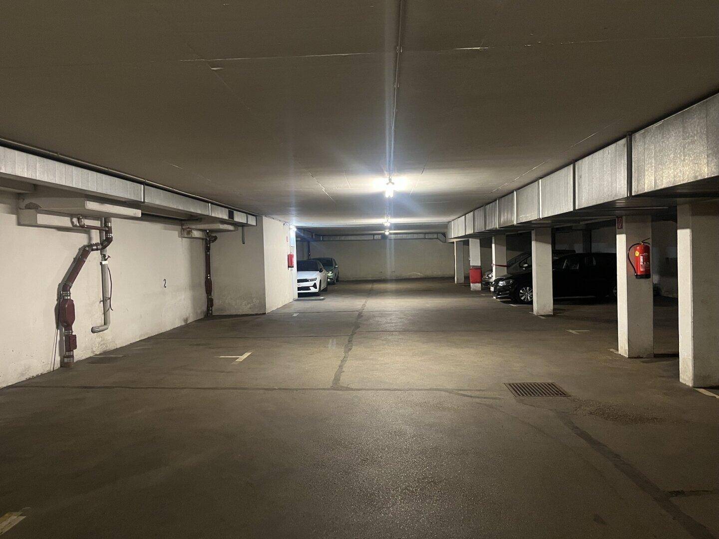 Geräumige Tiefgarage mit mehreren Stellplätzen und heller Deckenbeleuchtung.