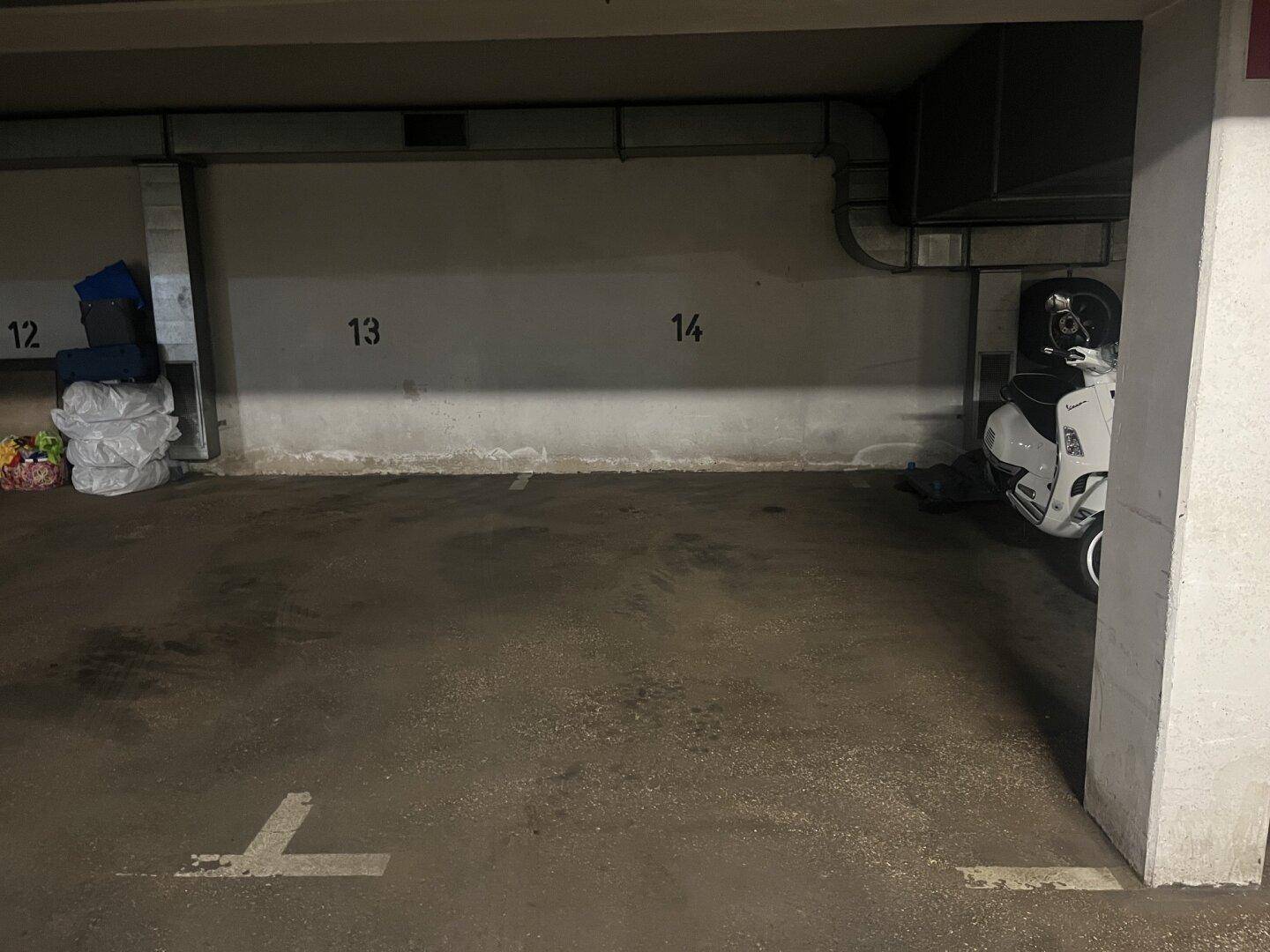 Einzelner Stellplatz in einer Tiefgarage mit Betonboden und Nummerierung an der Wand.
