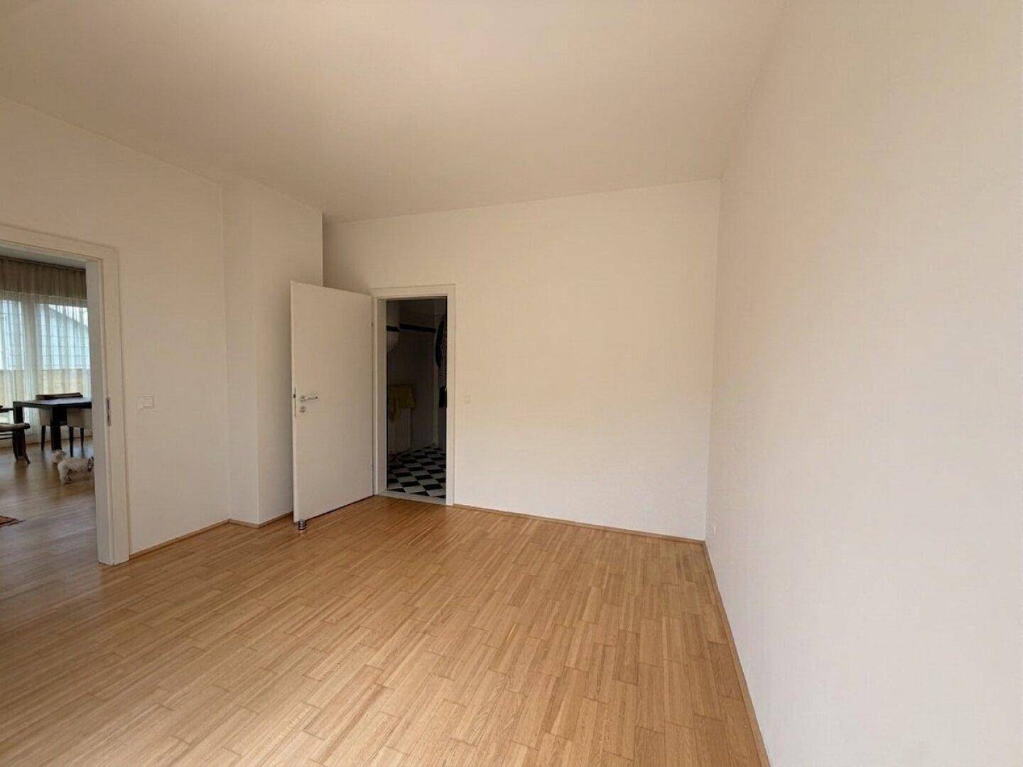 Leerer Raum mit Holzboden und weißen Wänden, der vielseitig genutzt werden kann.