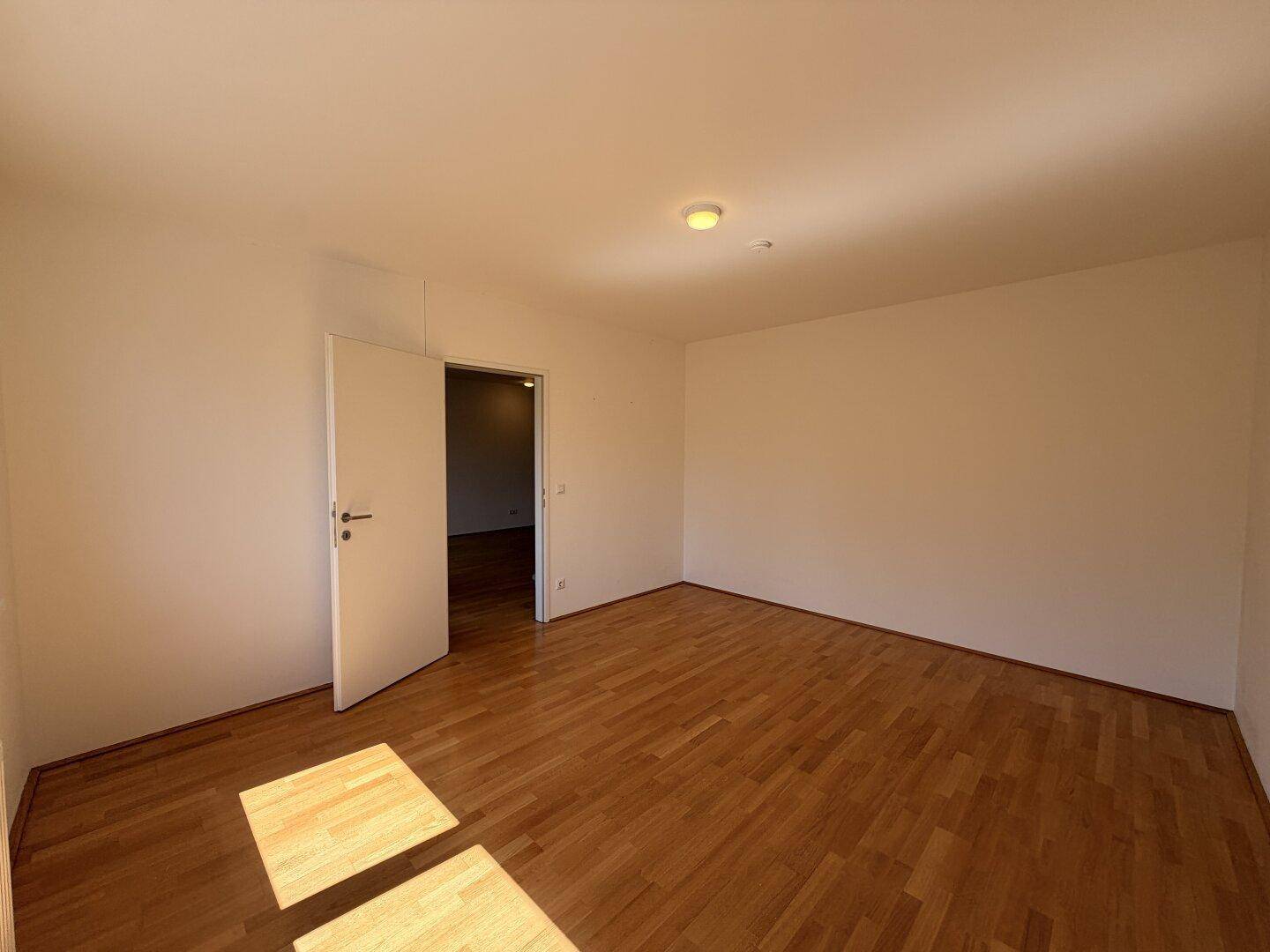 Geräumiges Zimmer mit Parkettboden und viel Tageslicht, ideal als Schlaf- oder Arbeitszimmer.