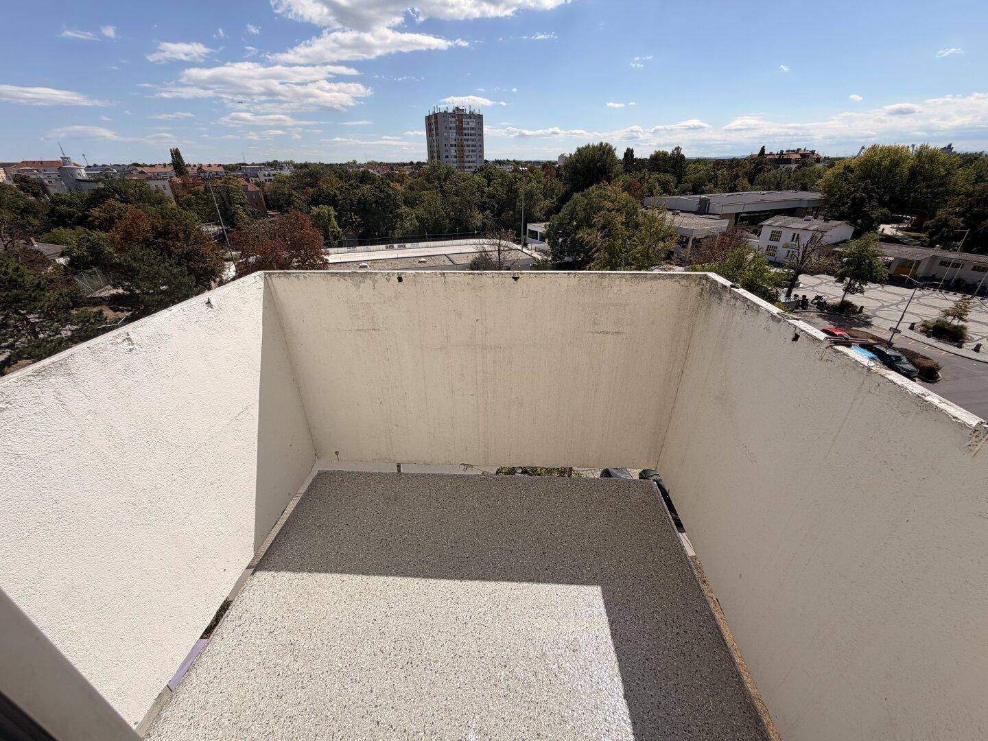 Leerer Balkon mit Blick auf die städtische Umgebung und weitere Gebäude in der Ferne.