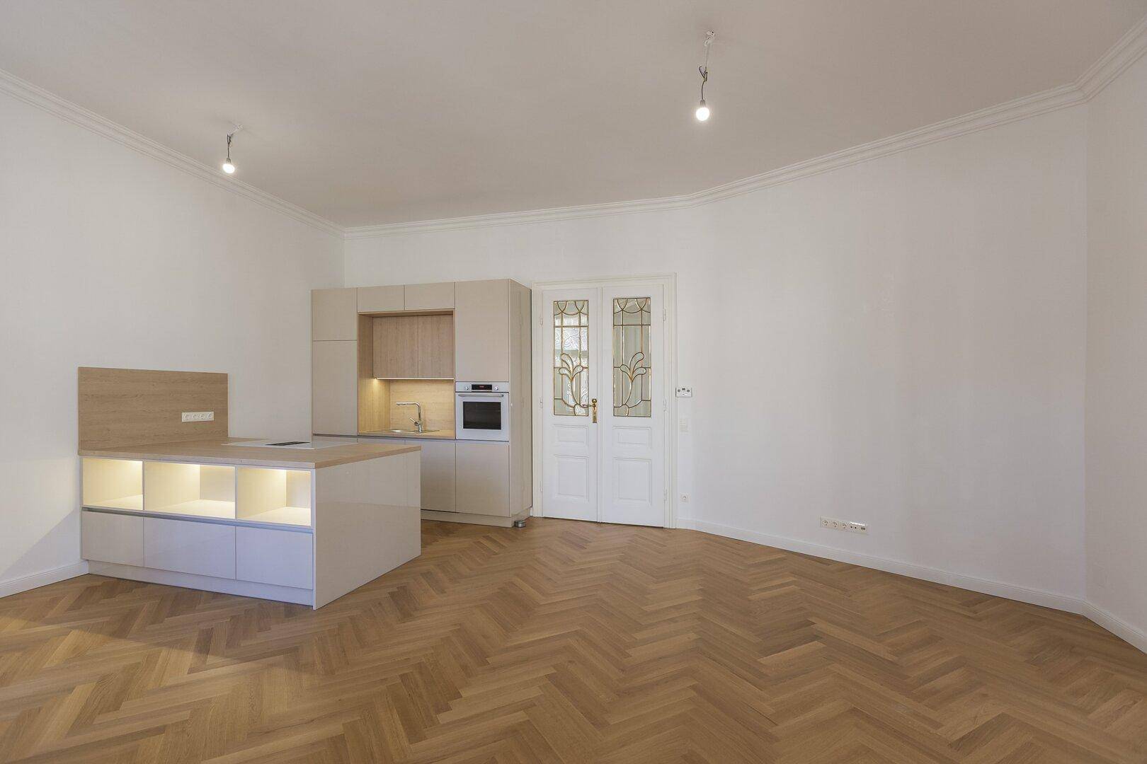 Offener Wohn- und Essbereich mit moderner Küchenzeile und eleganten Flügeltüren.