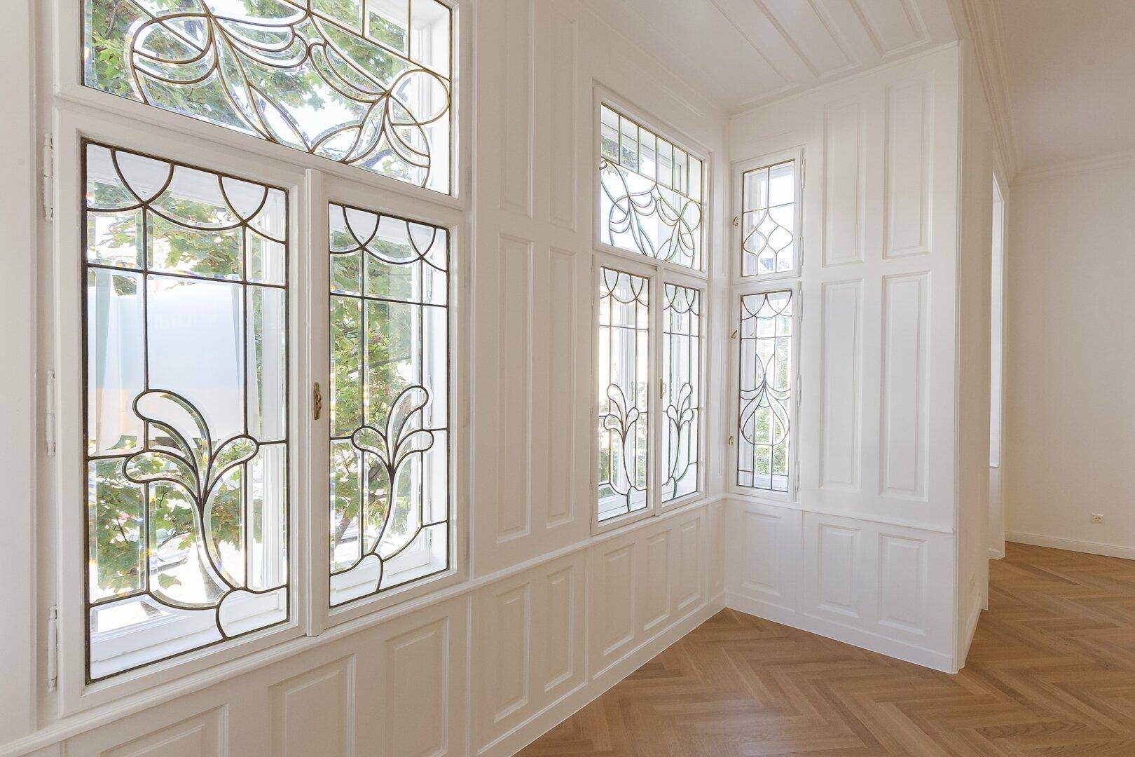 Detailansicht der kunstvollen Bleiglasfenster und der eleganten Holzvertäfelung im Erker.