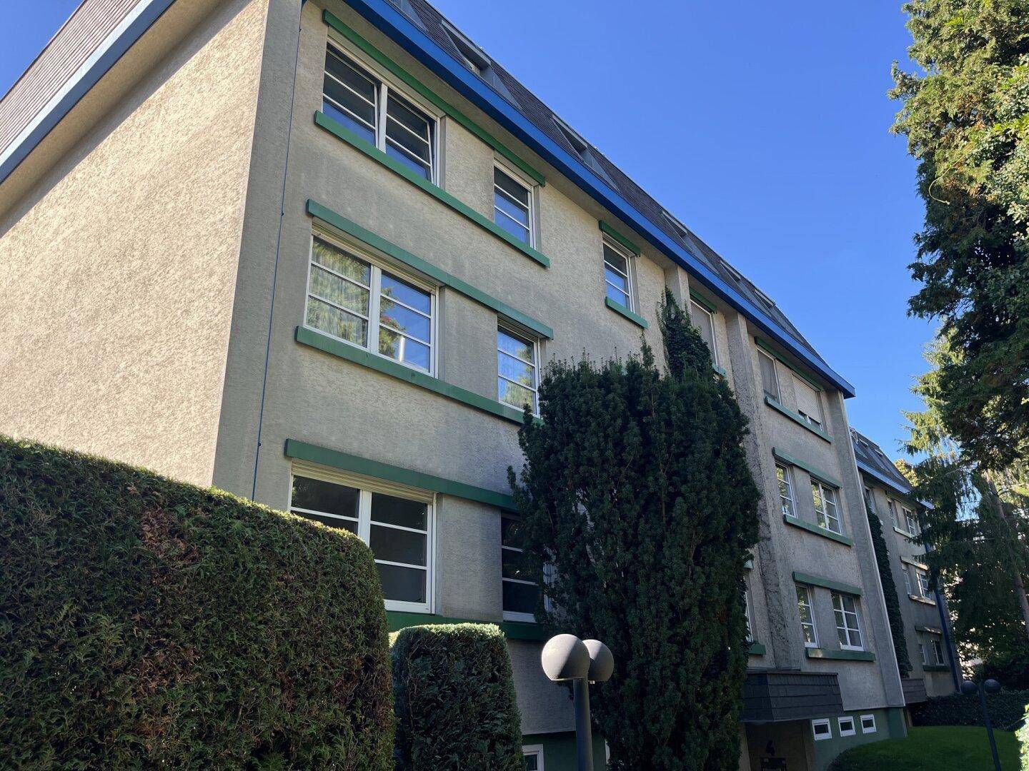 Mehrfamilienhaus mit grünen Akzenten an den Fenstern und einer gepflegten Fassade.