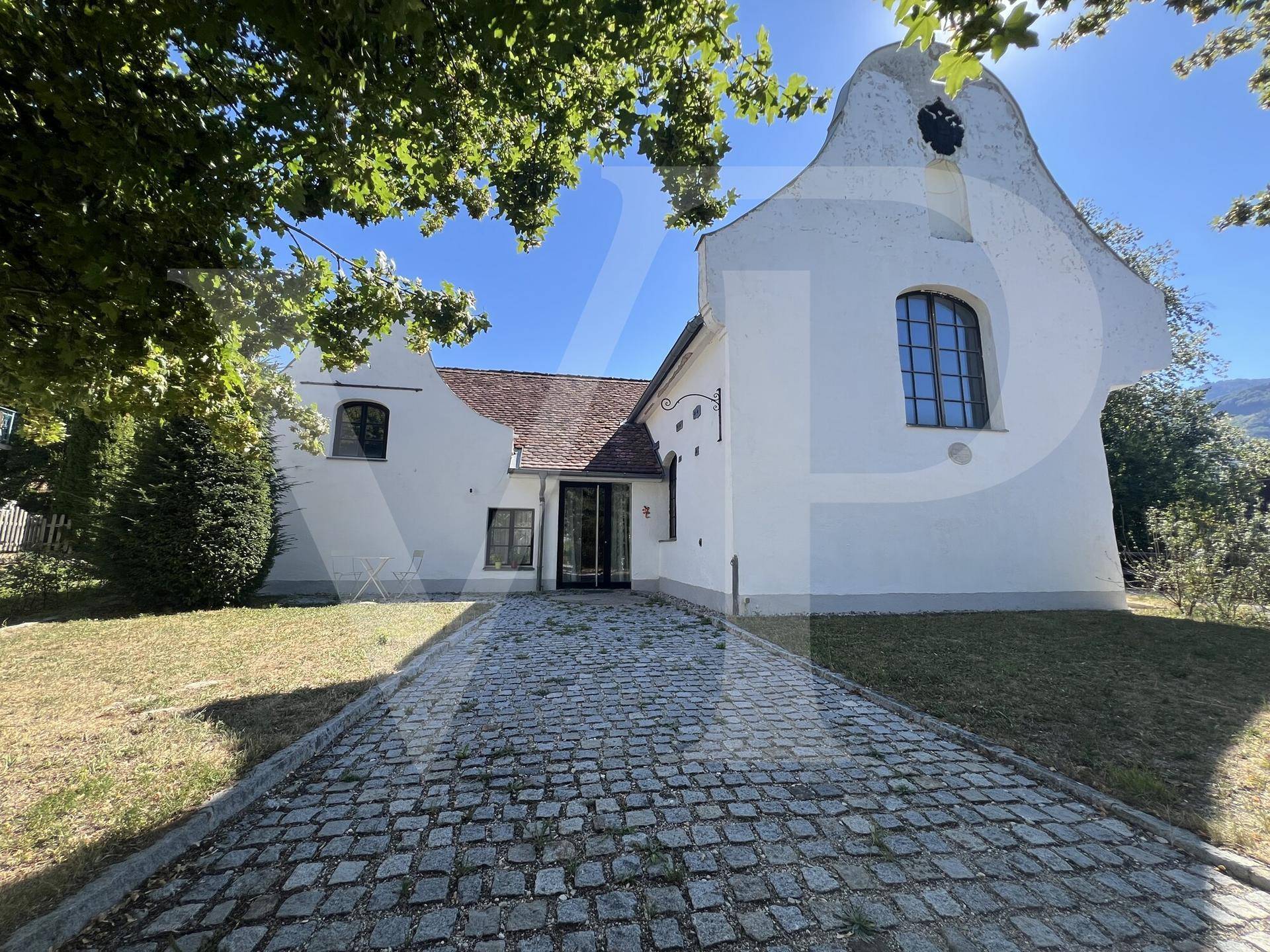 Ansicht der Gebäudefassade mit gepflastertem Zugangsweg unter blauem Himmel.